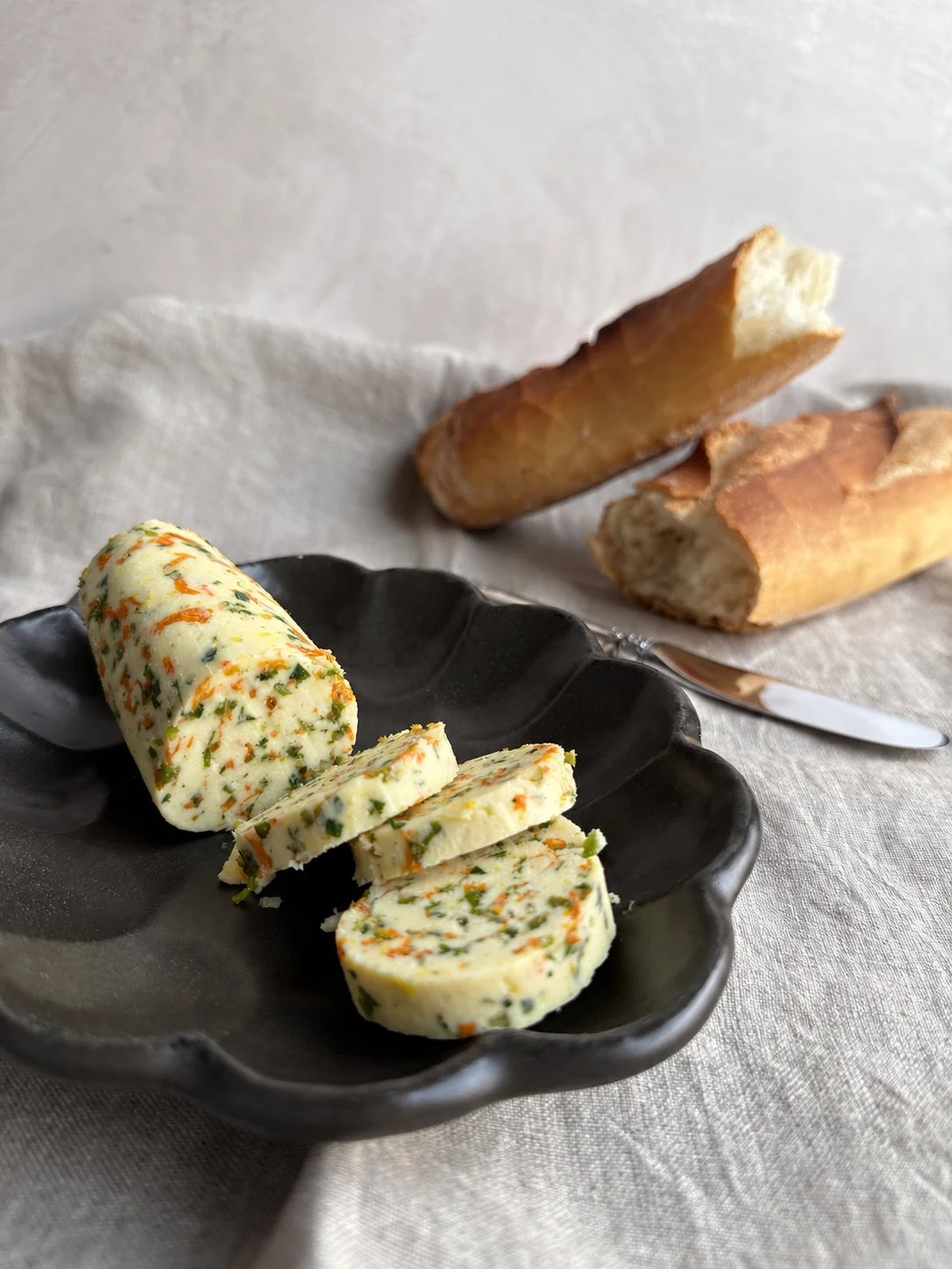 Close-up of squash blossom butter flecked with yellow petals, lemon zest and chives.