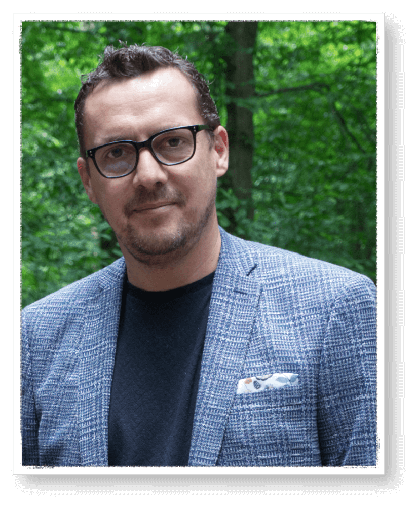Farbfoto von Jens Hasert, Bestatter in Oranienbaum und Sohn von Manfred Hasert; er trägt Brille, ein gemustertes Sakko und steht vor grünem, bewaldetem Hintergrund.