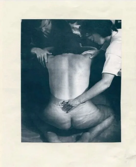 A person receiving a tattoo on their lower back from a tattoo artist.