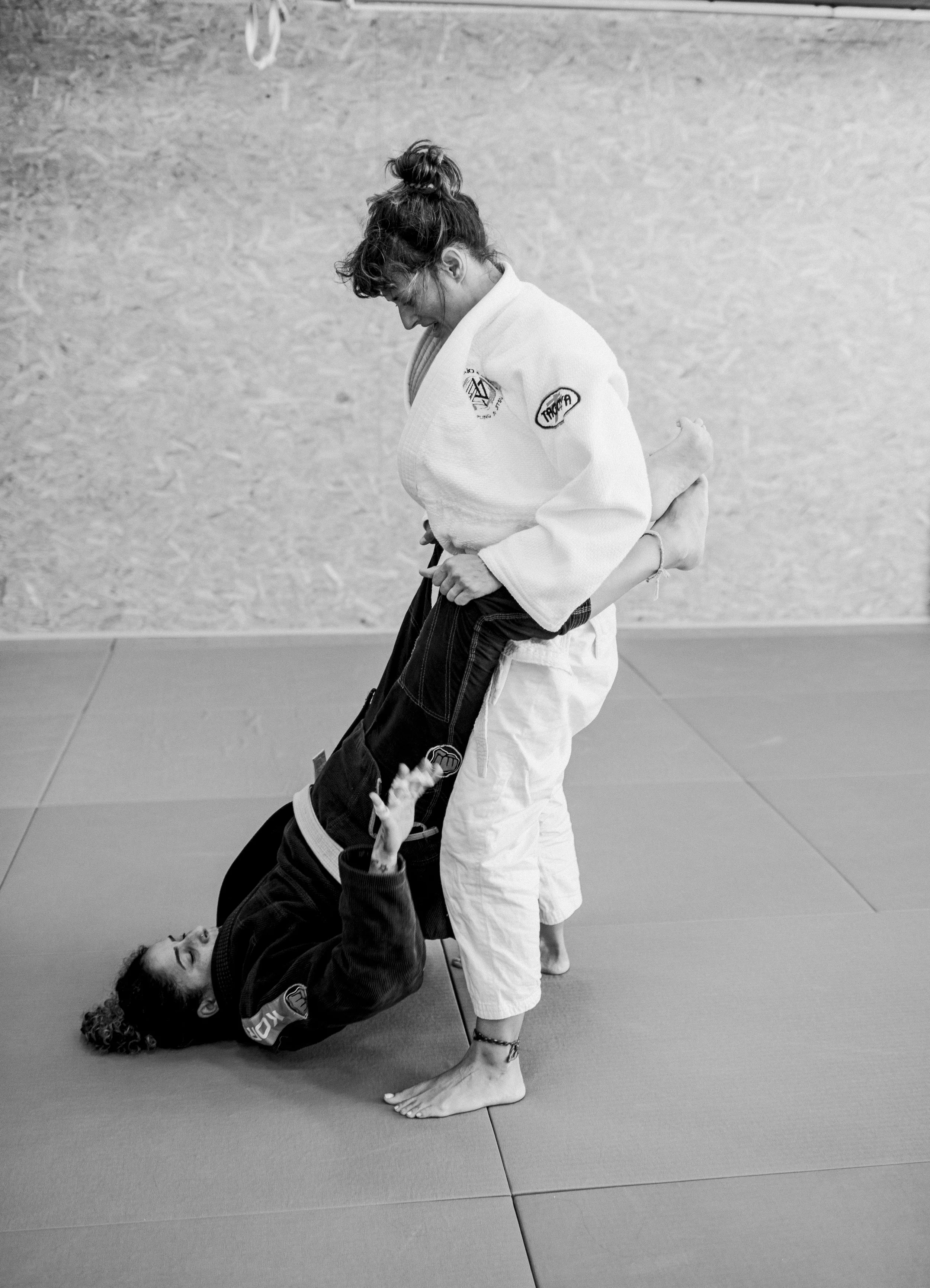 Chloë FitzGerald in a white GI holding up the legs of another woman in a dark GI