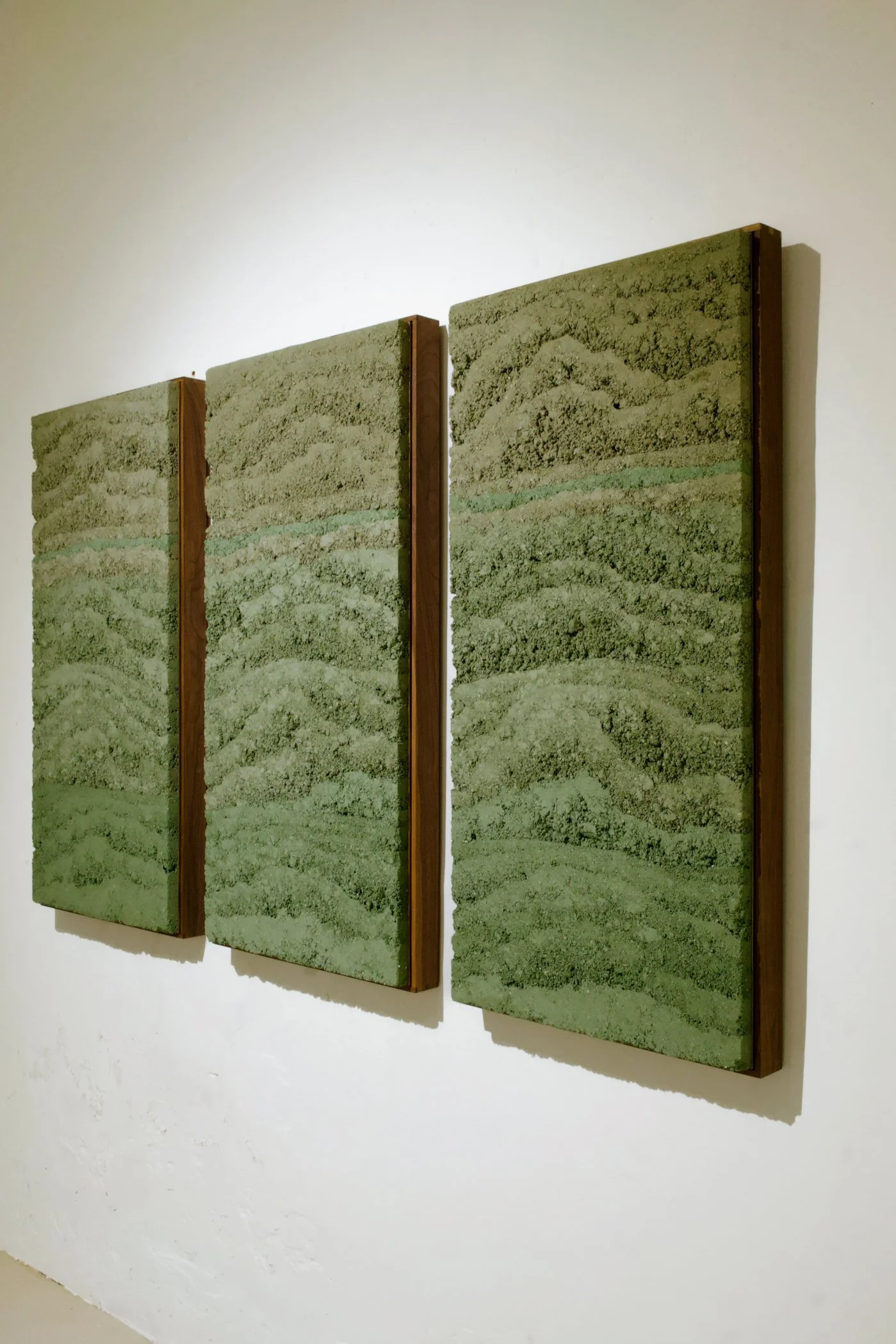 Angled view of Green Rammed Earth: Skyspace by Adam Weismann for Clayworks at Matiz Gallery Barcelona; abstract vernacular art triptych in rammed earth.