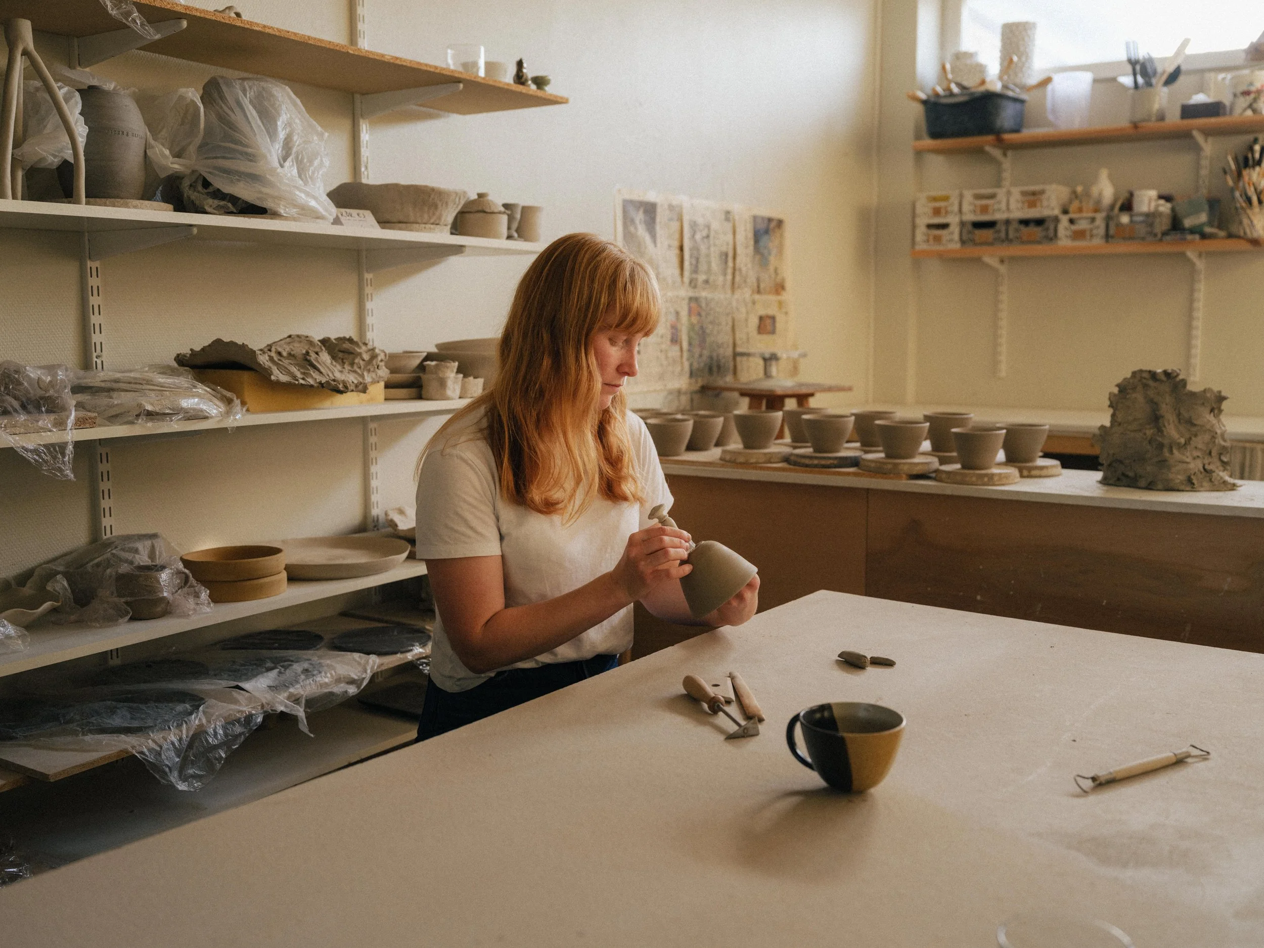 En kvinna som formar keramik på ett arbetsbord i en keramikverkstad.