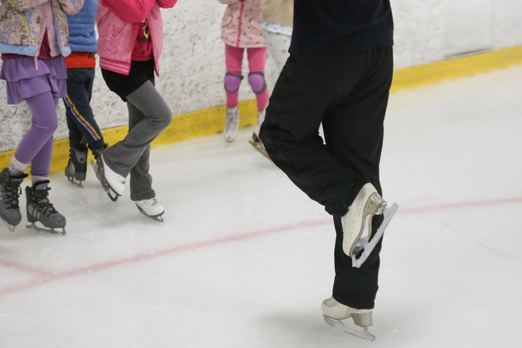 Skaters practicing on ice skills during figure skating camp in Austin at Skate VIDA