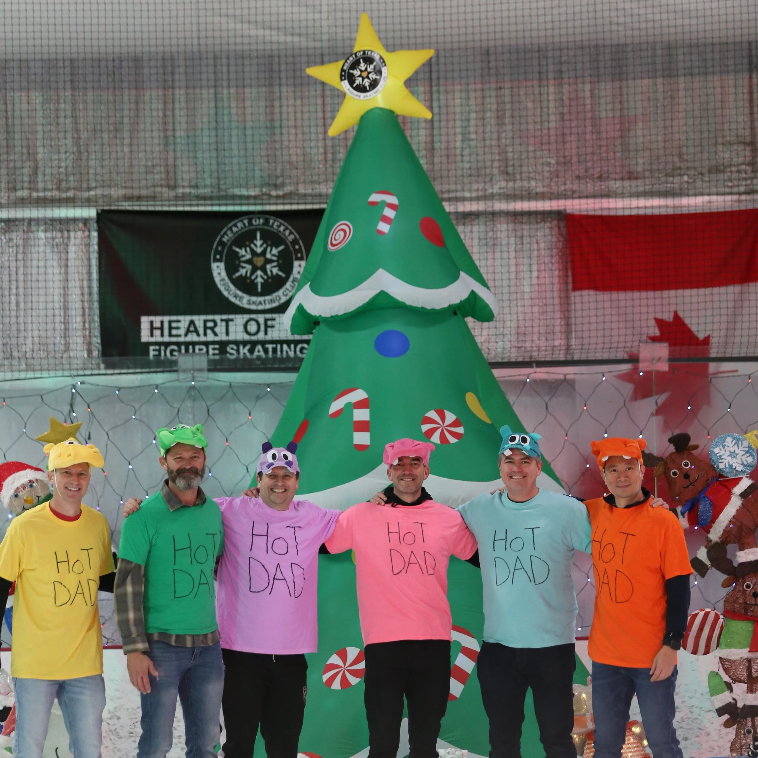Skate dads in hippo costumes posing in front of holiday display after holiday ice show