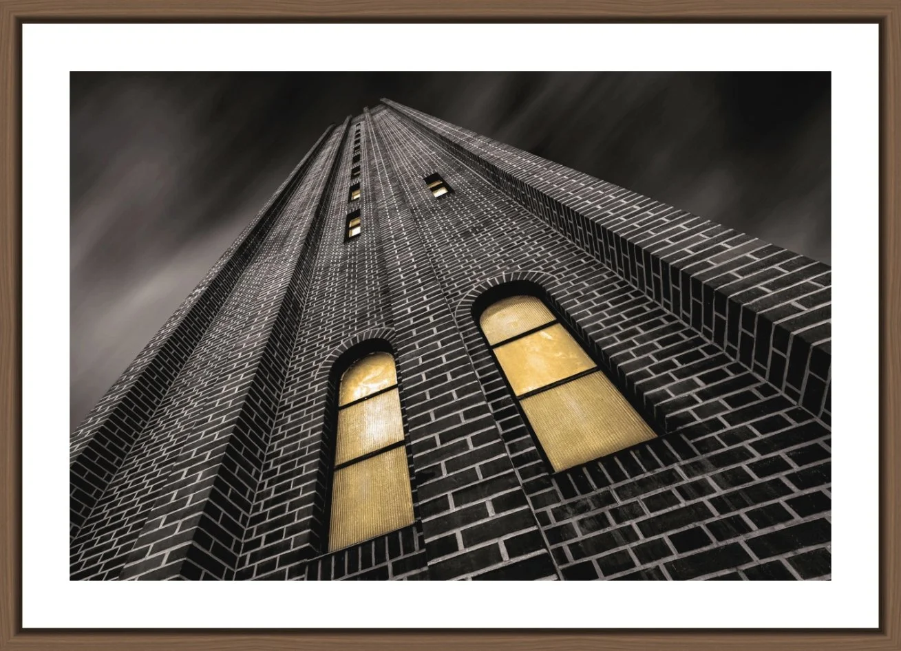 Aufnahme eines hohen Wolkenkratzers aus niedriger Perspektive bei Nacht, mit beleuchteten Fenstern und dunklem Himmel.