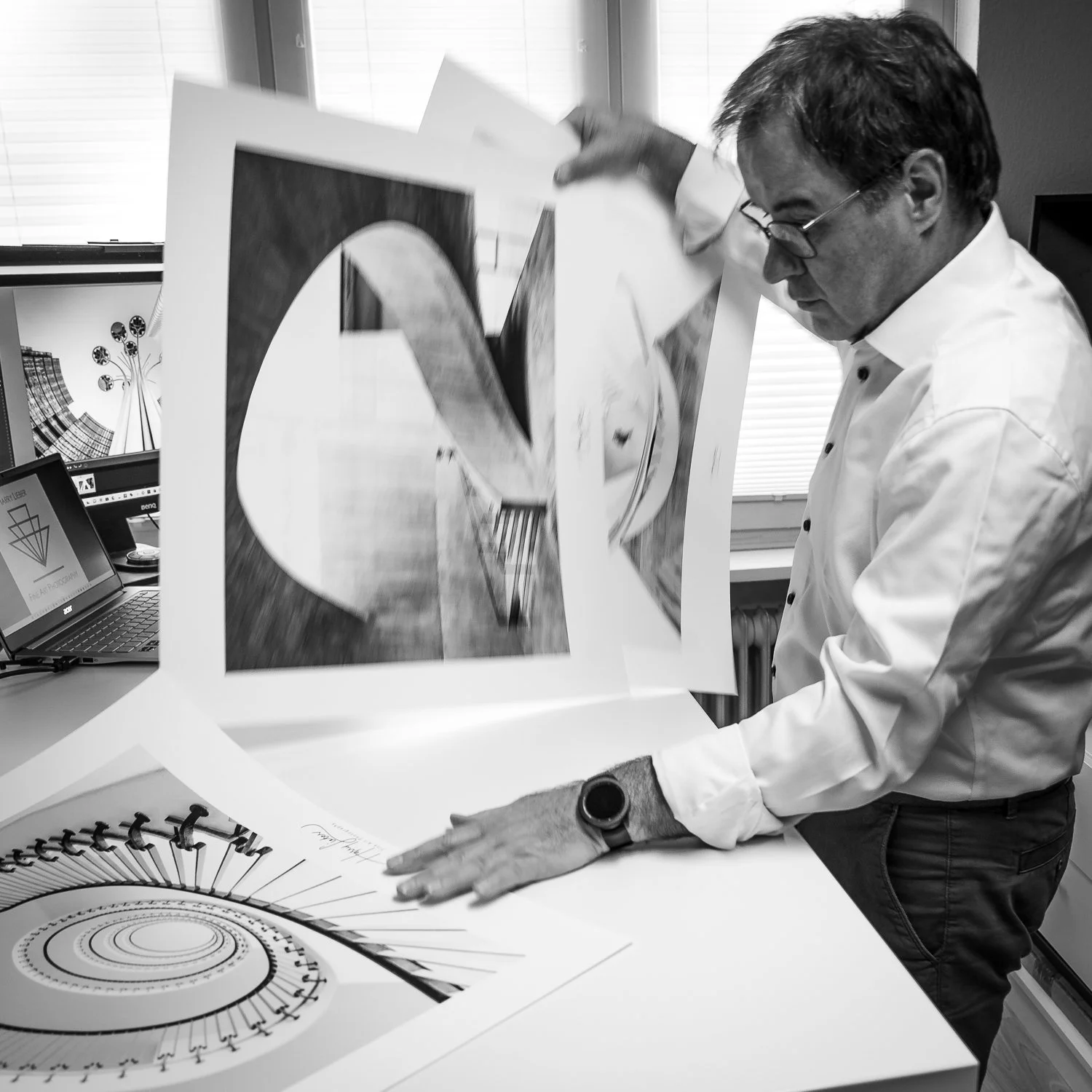 Mann arbeitet an einer Designpräsentation mit Skizzen und Poster in einem Büro.