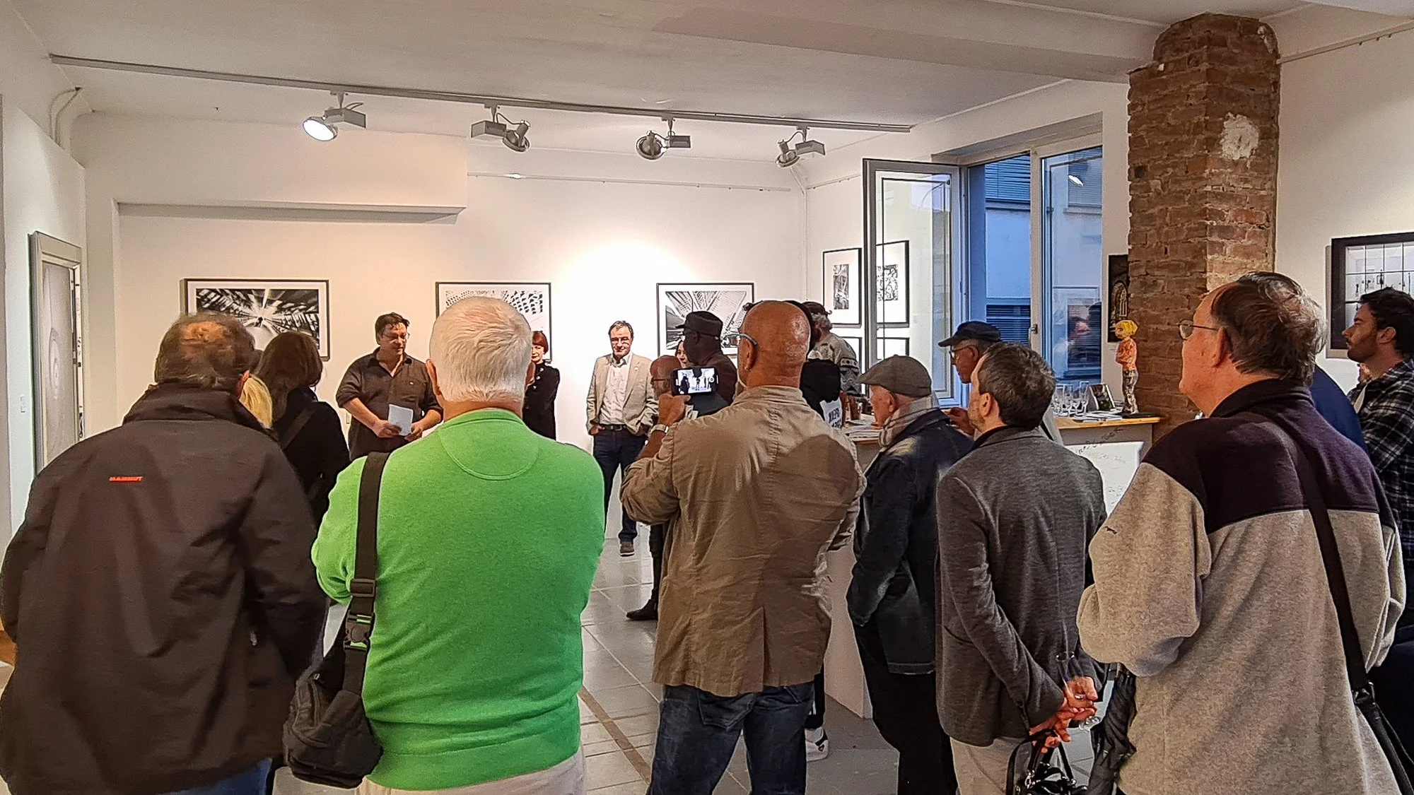 Menschen versammeln sich in einer Kunstgalerie bei einer Veranstaltung oder Eröffnung.