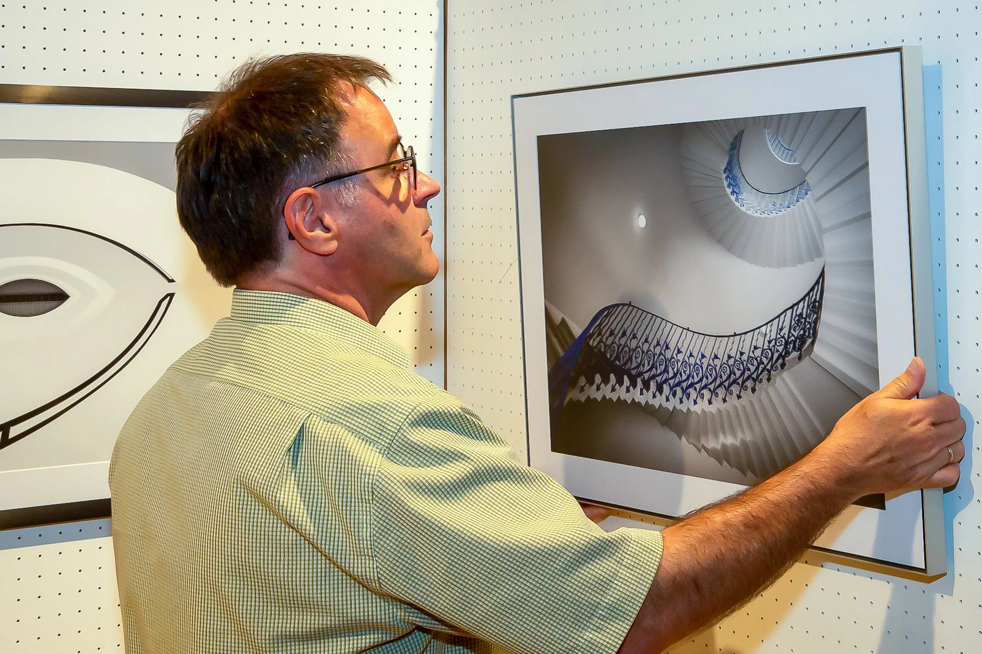 Mann betrachtet ein Kunstwerk einer spiralförmigen Treppe an einer Galeriewand.