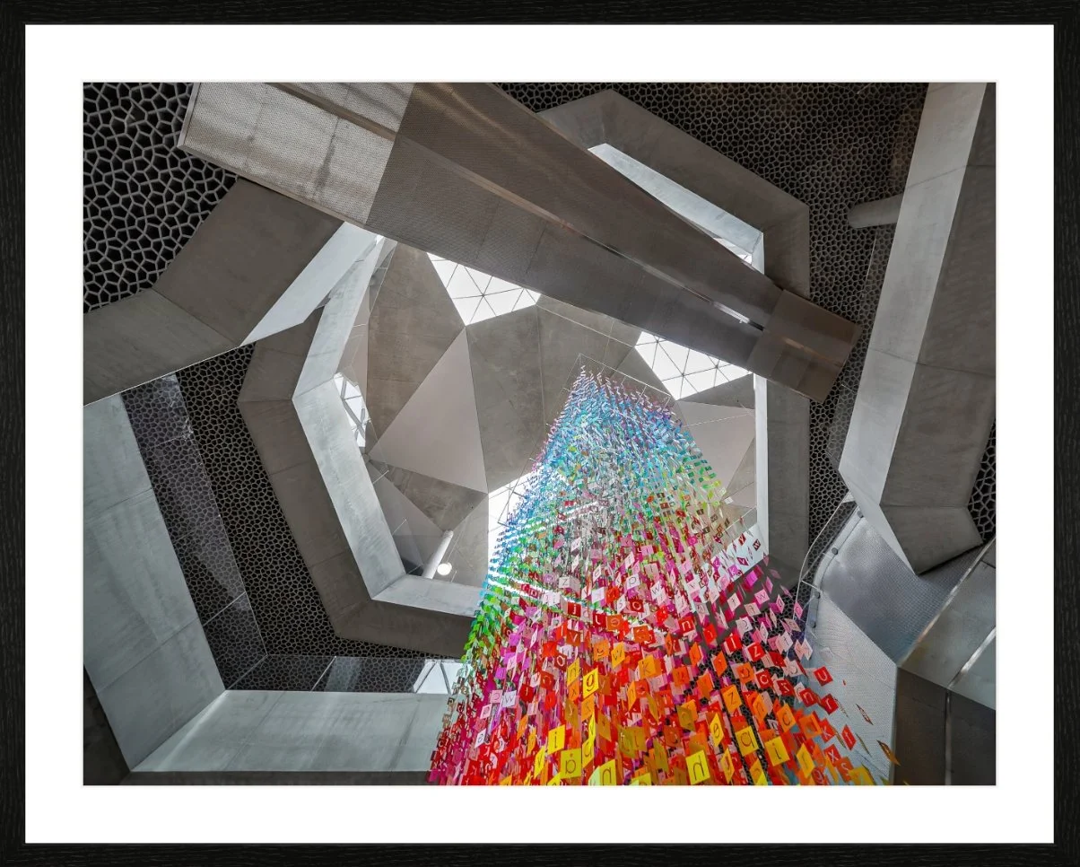 Innenansicht eines modernen, geometrischen Gebäudes mit einer bunten, dekorativen Auszeichnung, die nach oben hängt.