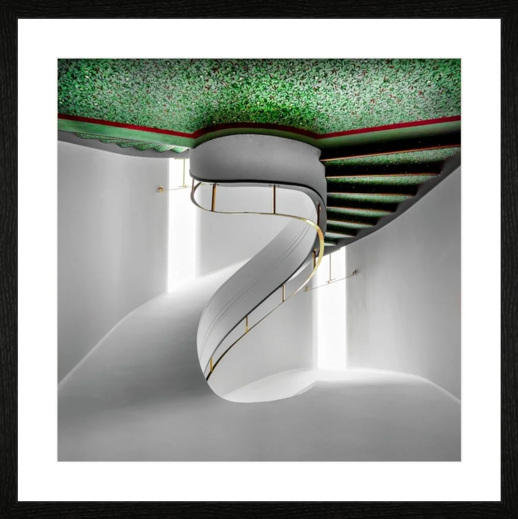 Ästhetische Treppe in einem modernen Gebäude mit weißem Geländer, grün gemustertem Teppichboden, Beleuchtung an den Wänden und einem Fensterauslass im Hintergrund.