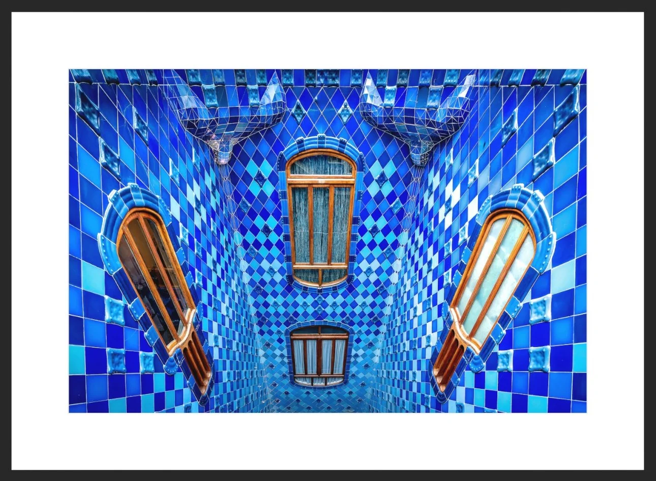 Innenraum einer blau gefliesten Wand mit drei verzerrt angeordneten Fenstern mit Holzrahmen.