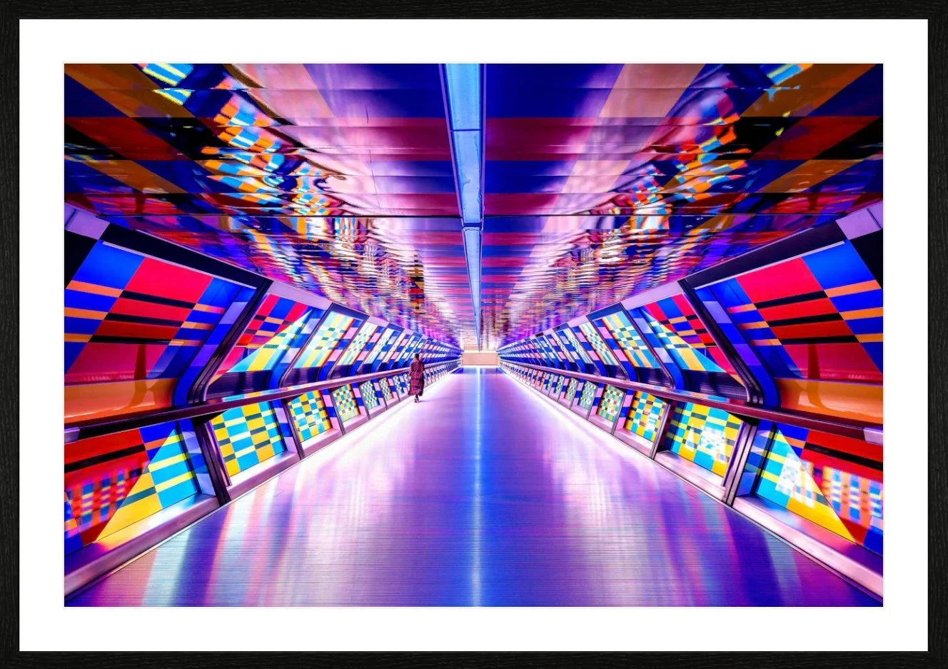 Ein farbenfroher, moderner Tunnel mit leuchtenden, geometrischen Mustern auf den Wänden und der Decke, mit einer einzelnen Person, die im Zentrum geht.