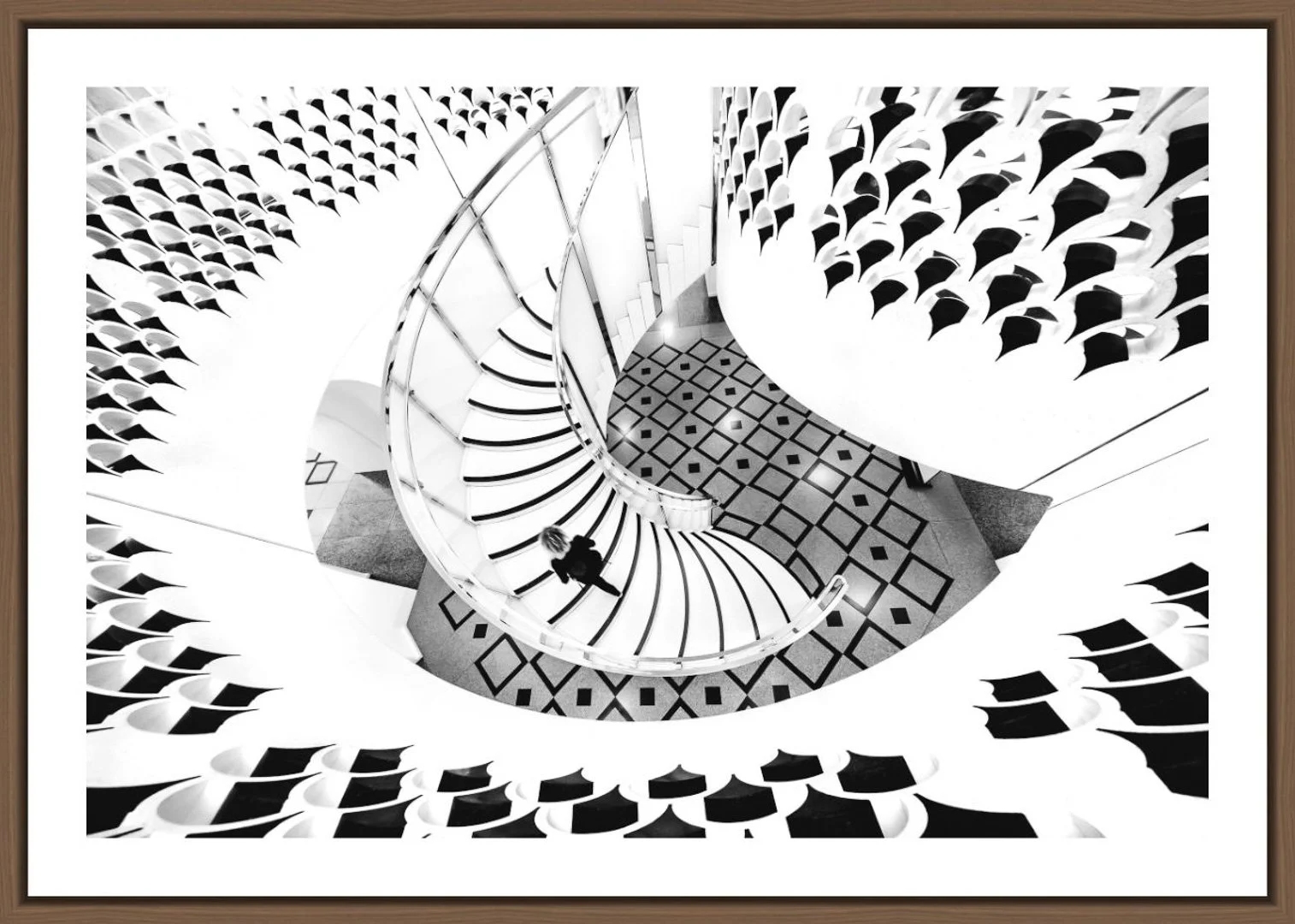 Schwarz-weiße spiralförmige Treppe in einem modernen Gebäude, Blick von oben auf einen einzelnen Menschen, geometrische Dessins am Boden.