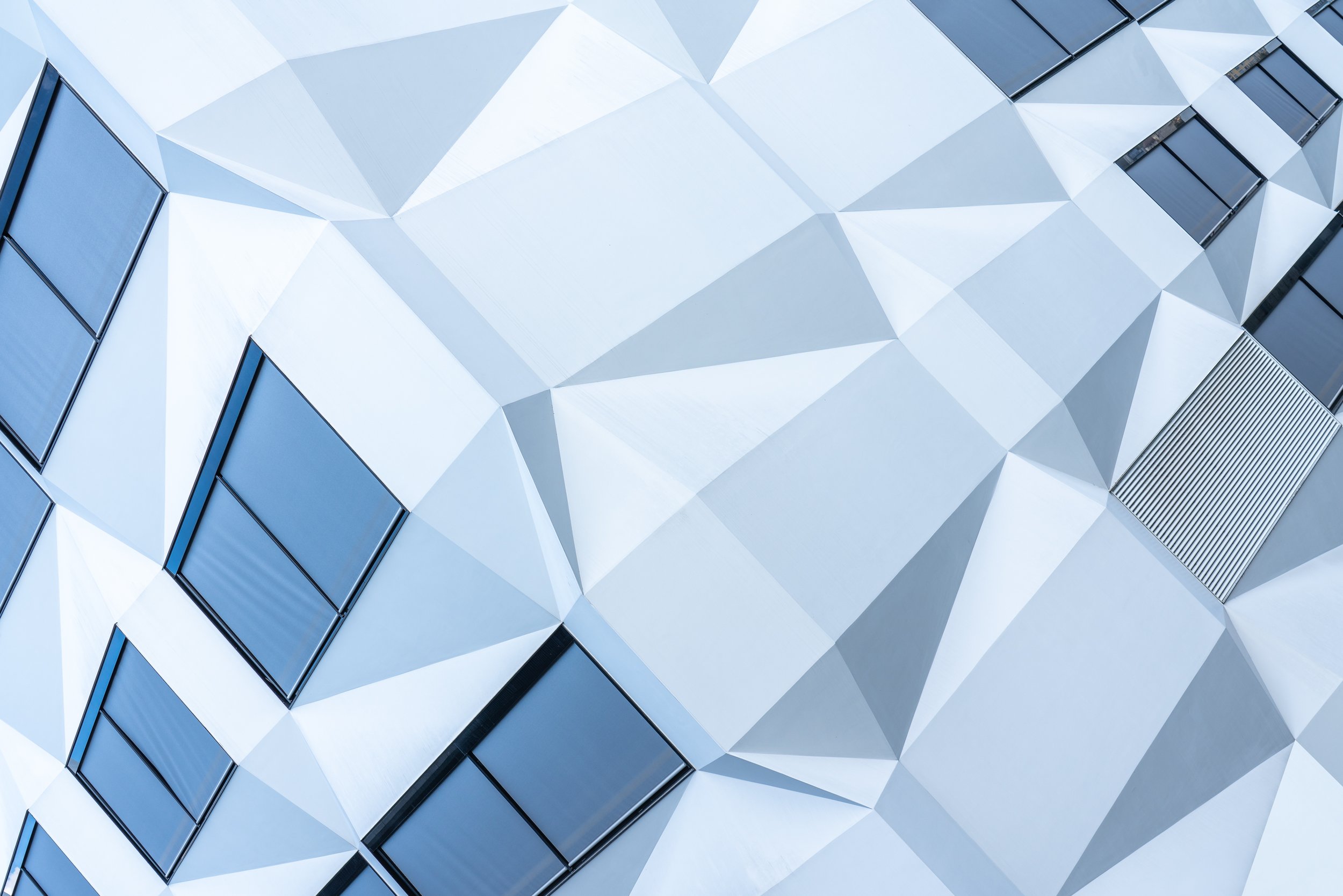 Modernes Gebäude mit geometrischer Fassadengestaltung aus weißem Material und schwarzen Fensterrahmen