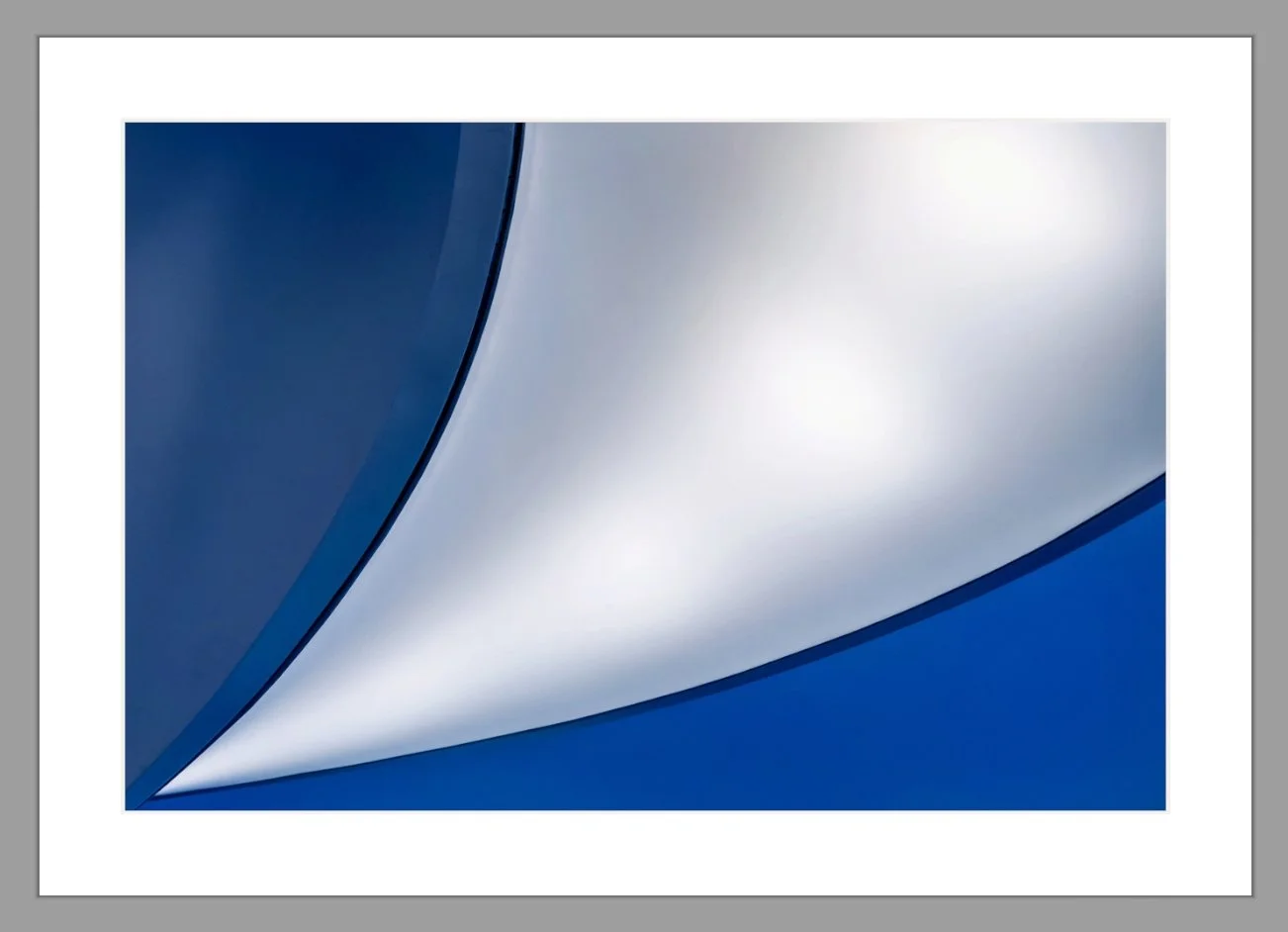 Naheaufnahme eines blauen und silbernen Autoteils mit glatten, gewölbten Oberflächen.