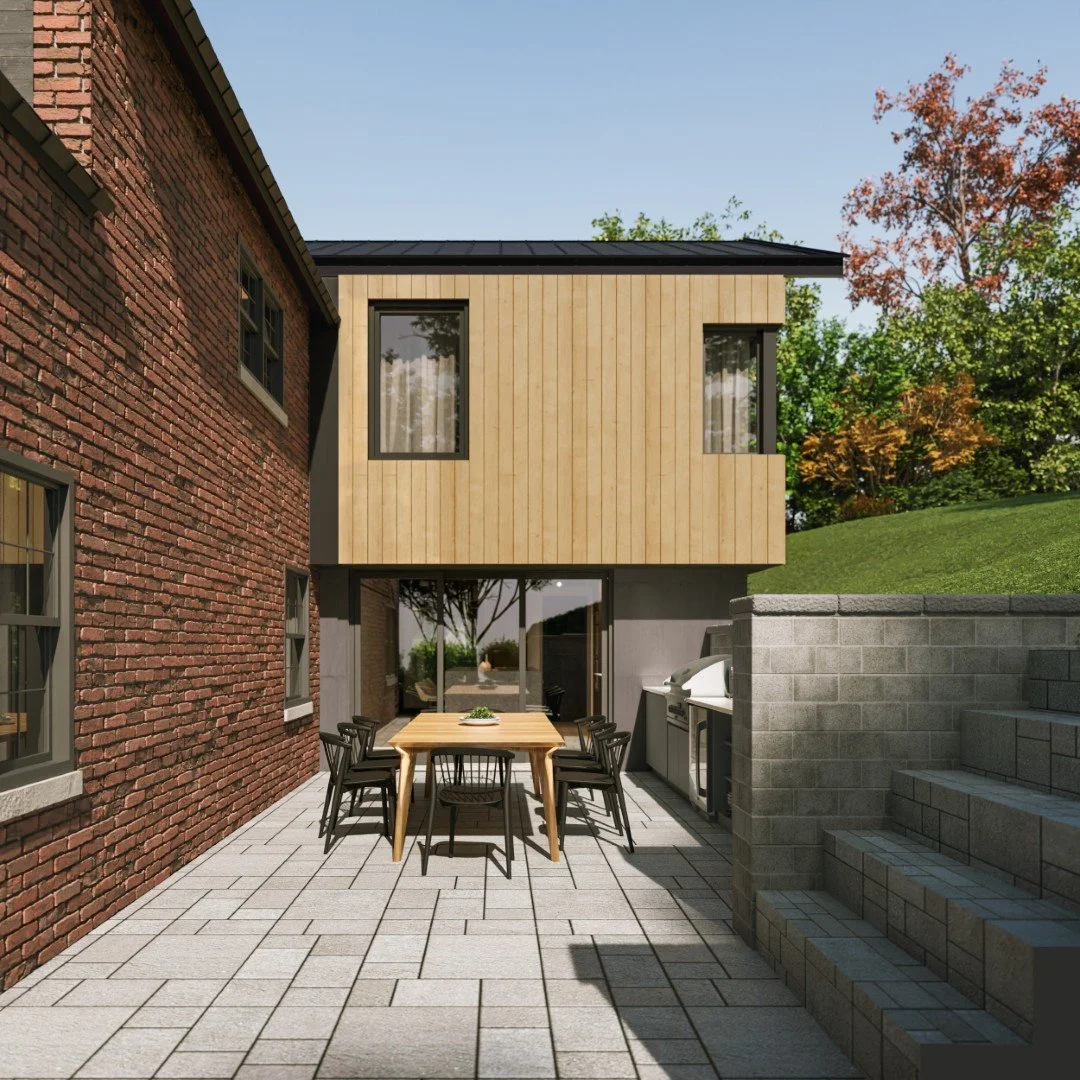 Modern backyard patio with a dining table, chairs, and outdoor grill, adjacent to a two-story house with brick and wood siding, surrounded by a green yard and trees.