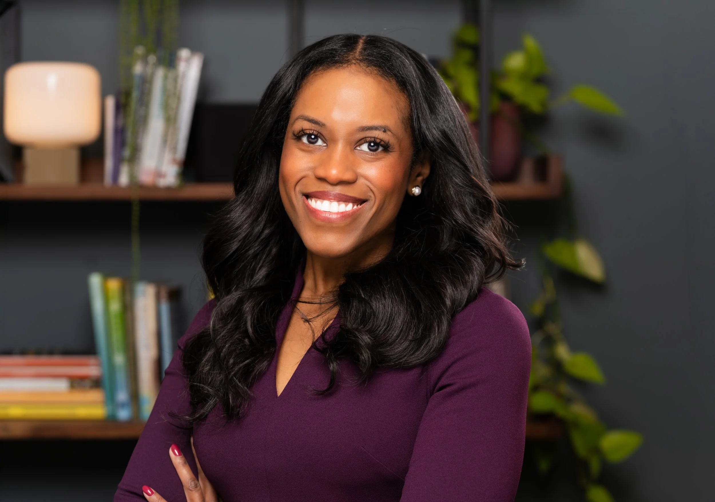 A smiling psychiatrist with long black hair wearing a red top outdoors in a green park.