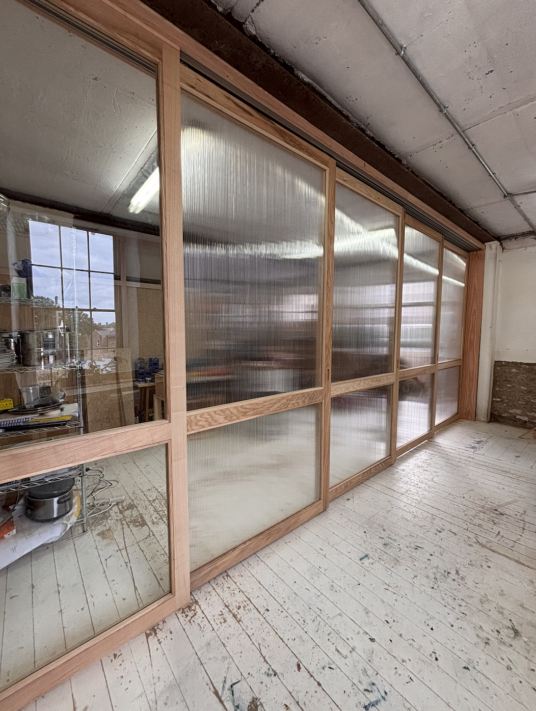 Professional joiner installing handcrafted timber sliding partitions at Silk Mill Studios in Frome