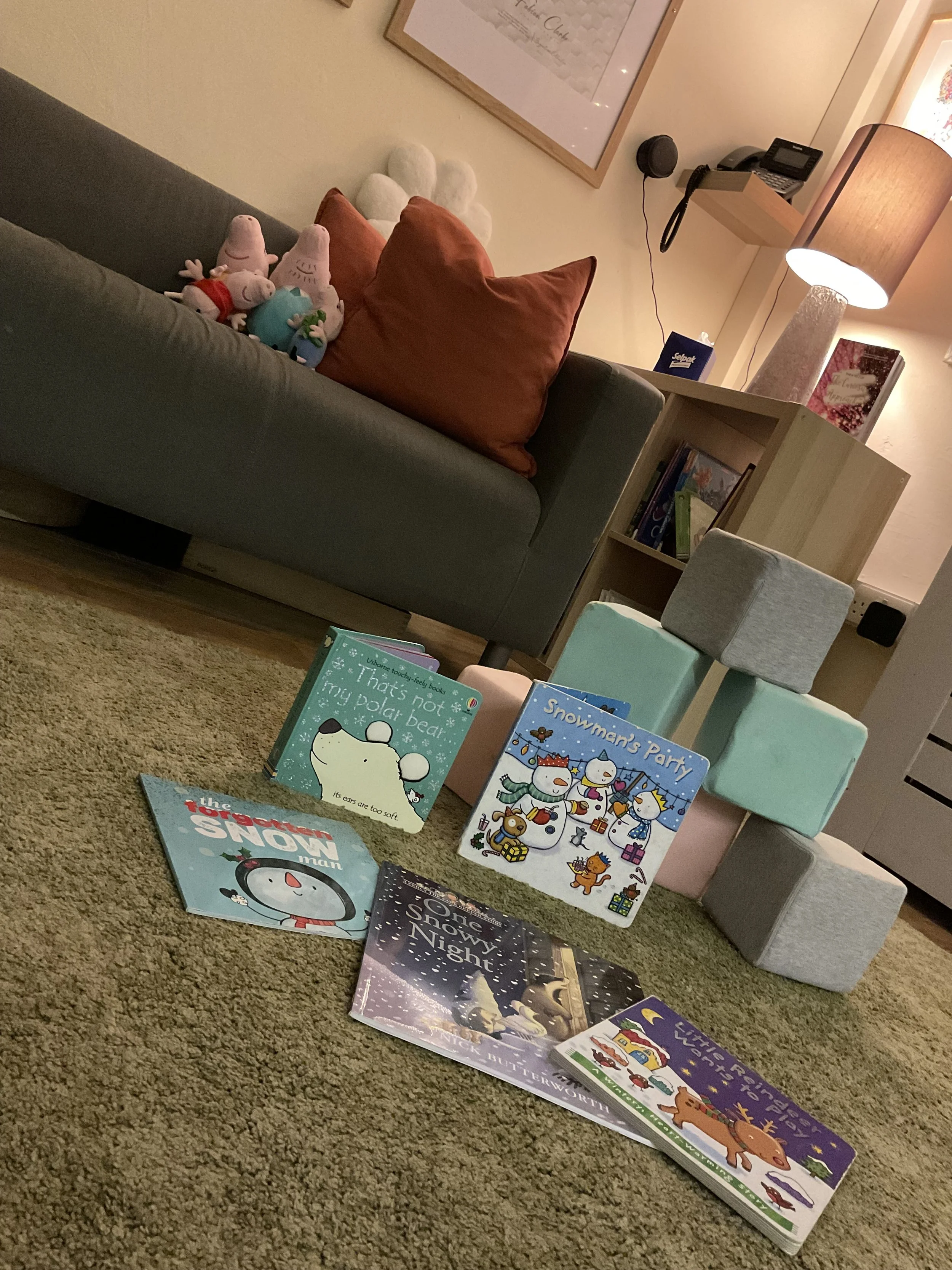 Scenic view of a lake surrounded by rolling green hills and tall mountains with partly cloudy sky.