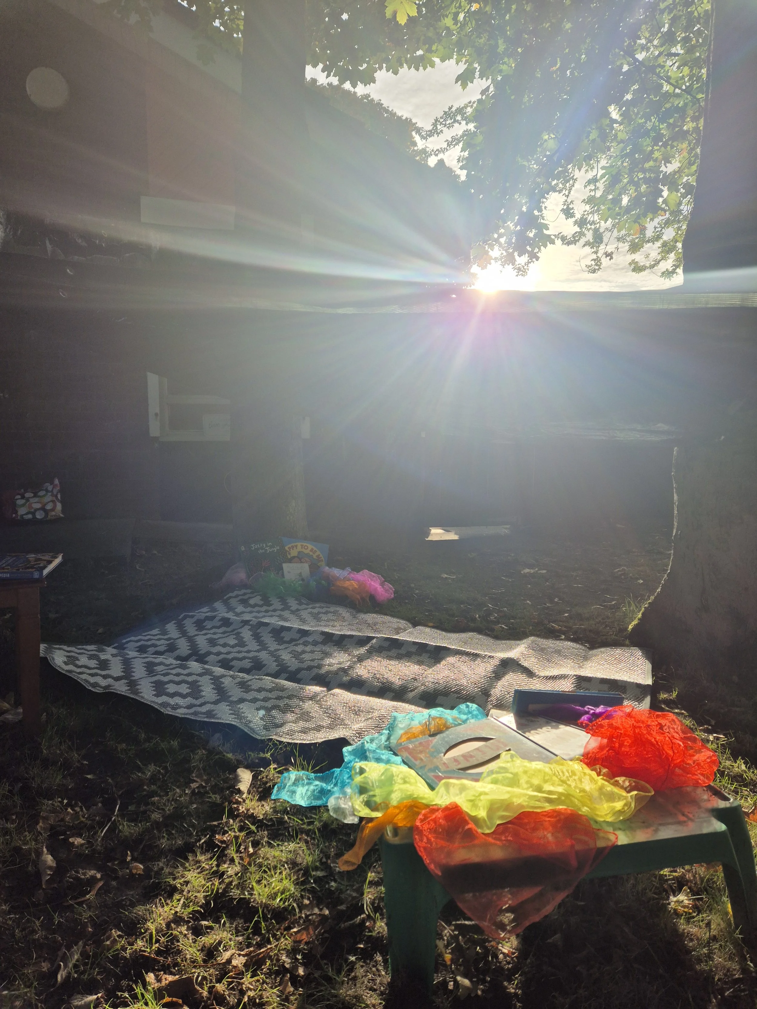 Modern wooden building in a mountain landscape with a large glass window showing two people inside.