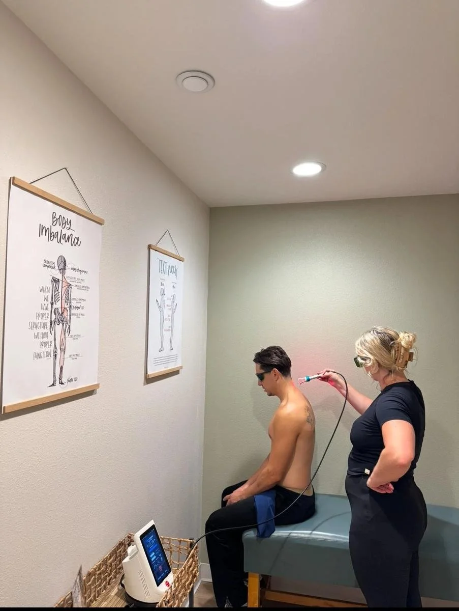 Chiropractor applying cold laser therapy to a patient's shoulder with safety glasses