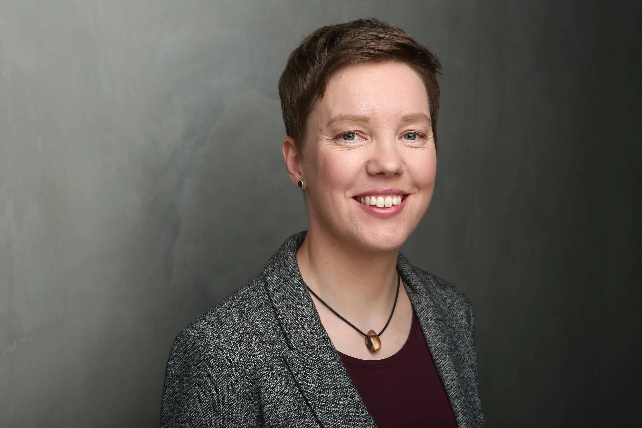 Franziska Ritter im Anzug vor einer Betonwand.