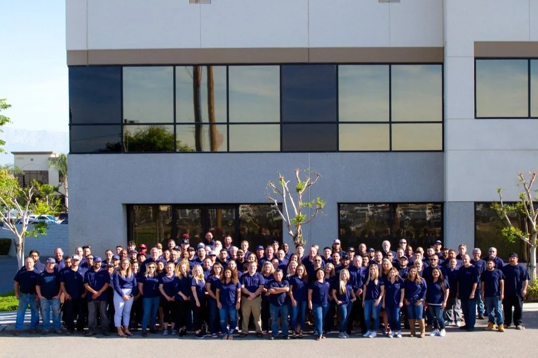 Group of NCI employees standing in front of their office building.