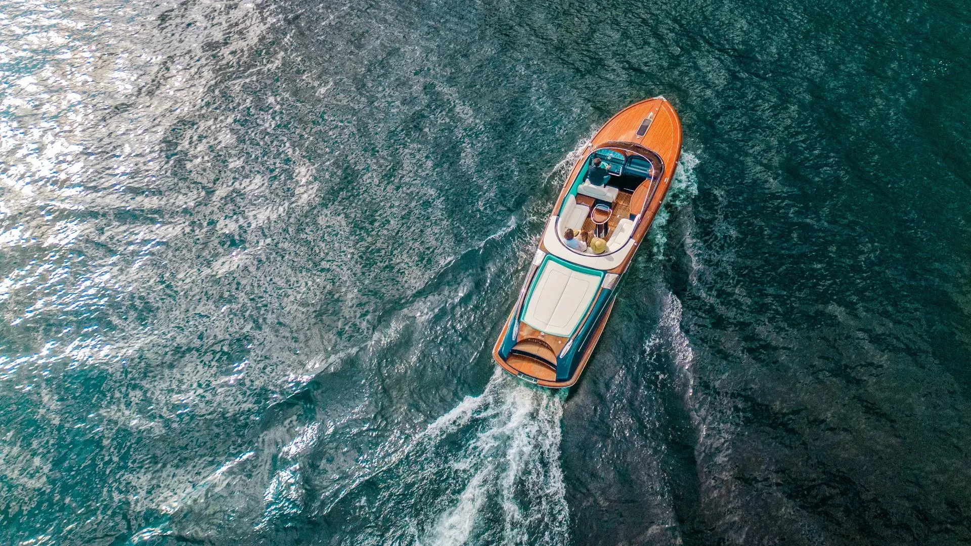 Wooden boat with a romantic couple traveling across a deep blue lake.