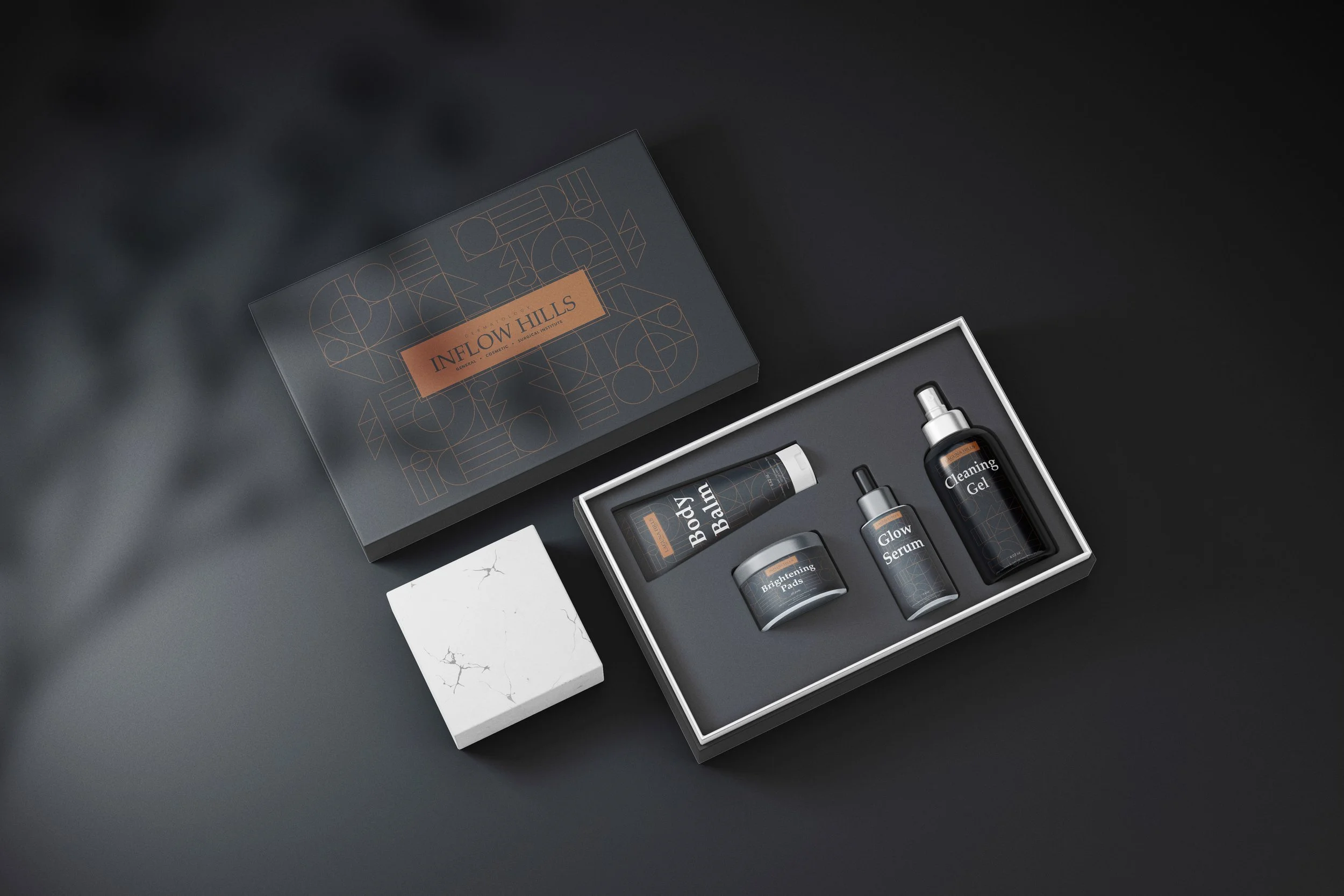 A set of skincare products titled "Inflow Hills" in a black box with a geometric pattern. The products include Brightening Pads, Body Balm, Glow Serum, and Cleaning Gel, arranged neatly inside an open box on a dark surface.