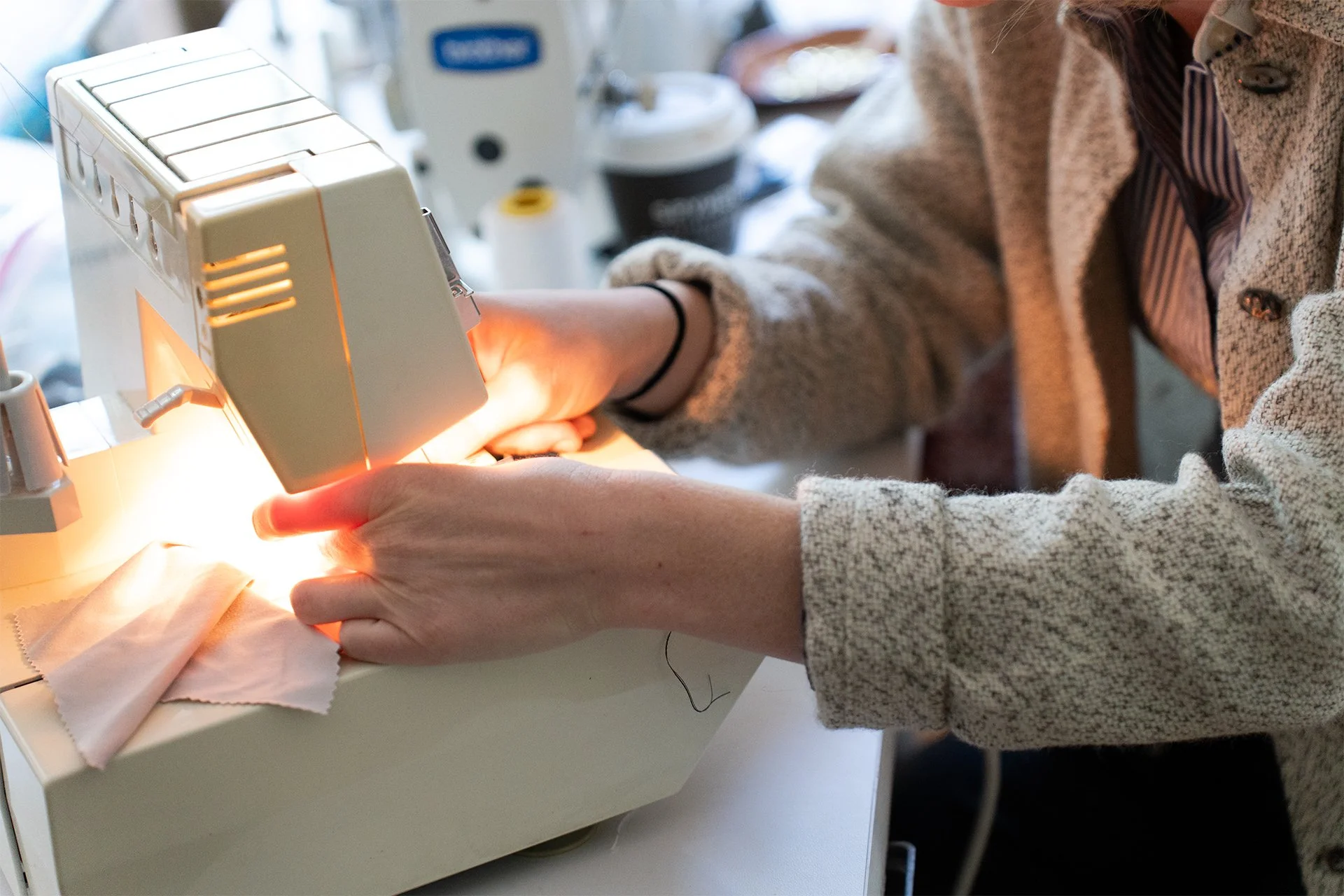 Person sewing fabric on a sewing machine in a workshop.