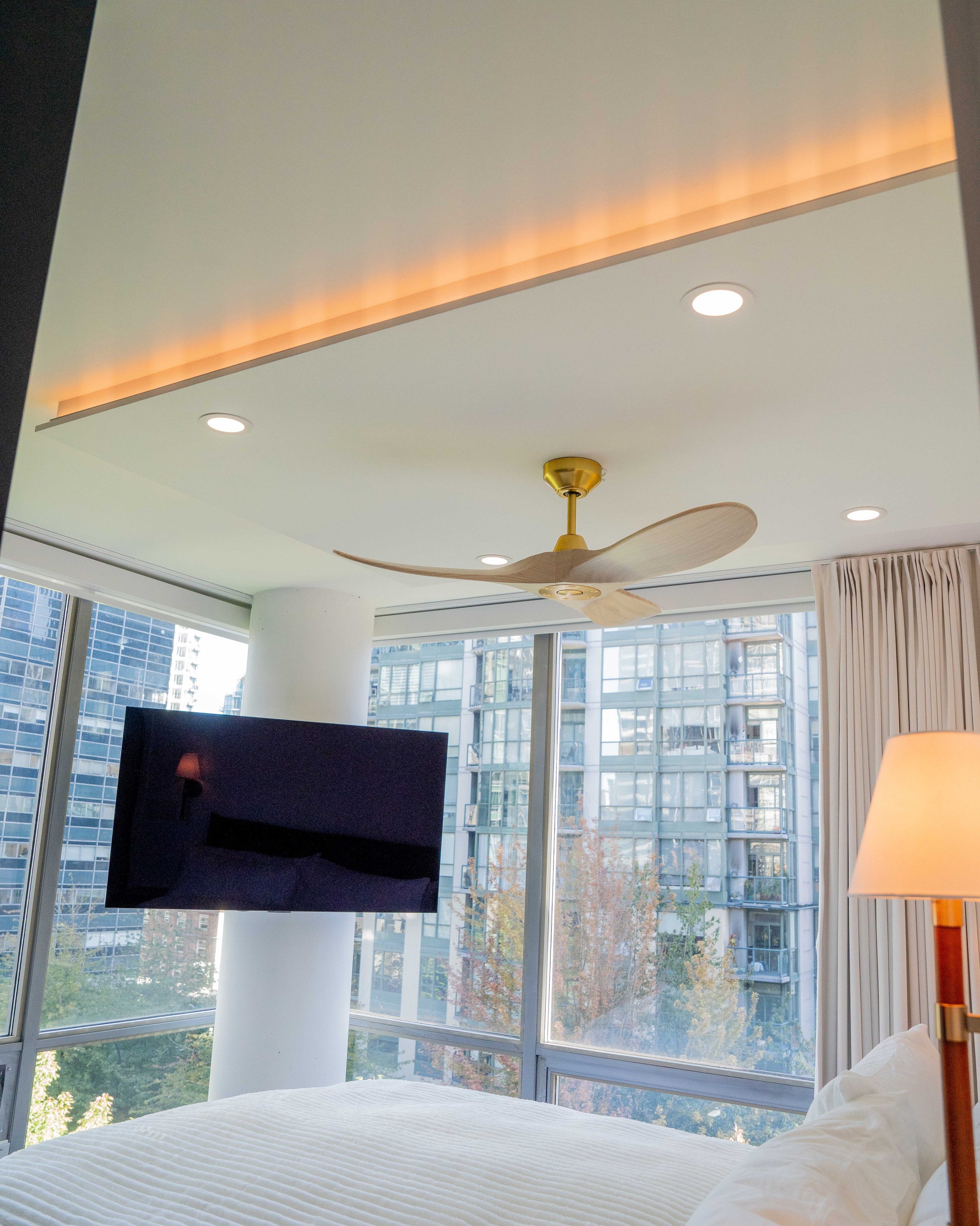 West Georgia condo renovation by WorkPro Contracting: Bedroom photograph featuring accent drop-down ceiling, custom lighting, and a view of the bedroom window with a remote controlled blind system