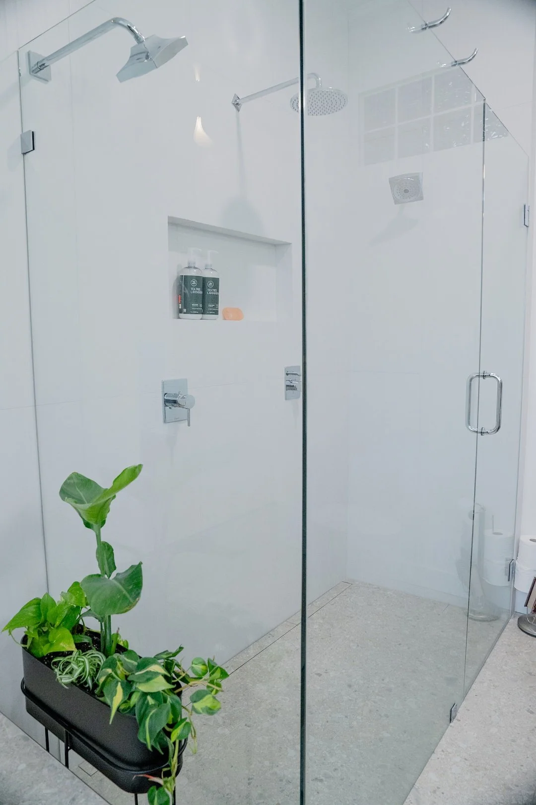 Image of a WorkPro Contracting bathroom renovation featuring a large curbless walk in glass enclosed shower with a rainhead shower and two showerheads