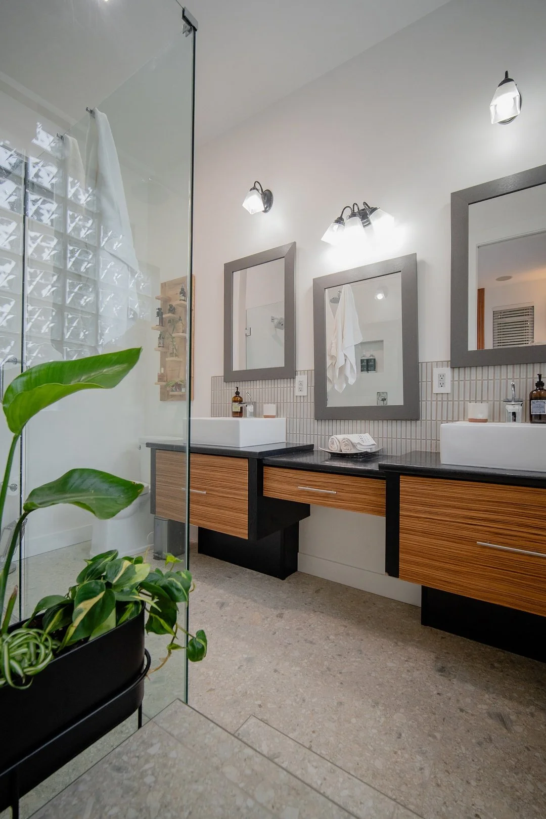 Image of a WorkPro Contracting bathroom renovation featuring a large curbless walk in glass enclosed shower and floating bathroom countertops