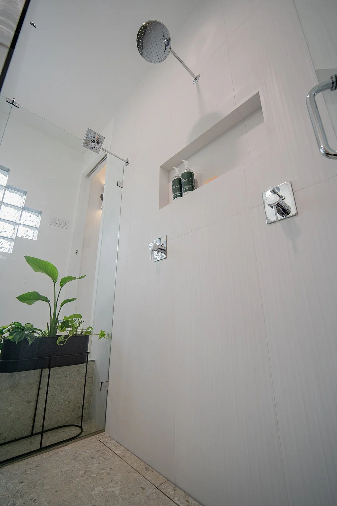 Image of a WorkPro Contracting bathroom renovation featuring a large curbless walk in glass enclosed shower with a rainhead shower and two showerheads
