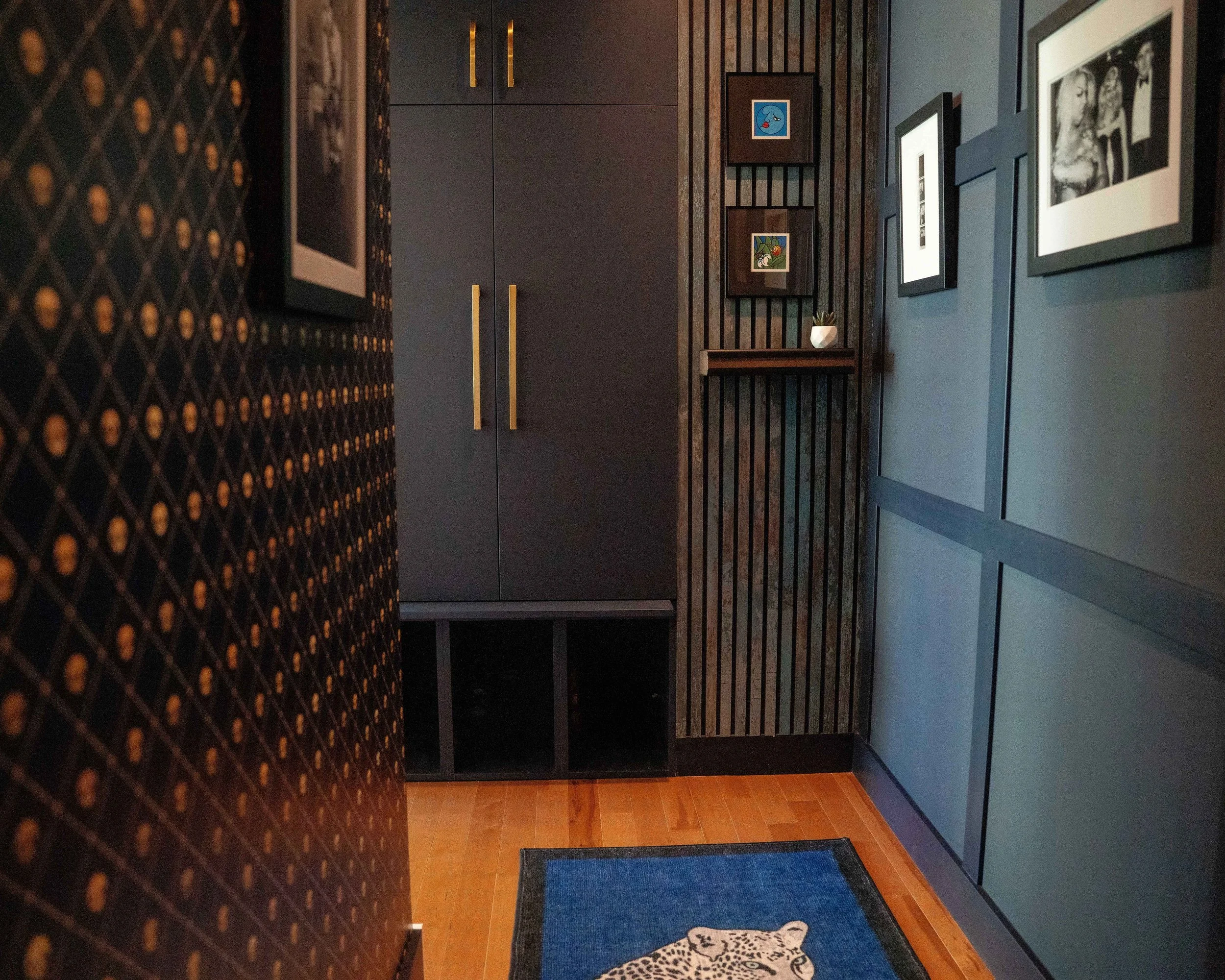 WorkPro West Georgia Condo Renovation: Photograph of condo entryway, featuring dark blue walls, custom storage, and curated artwork