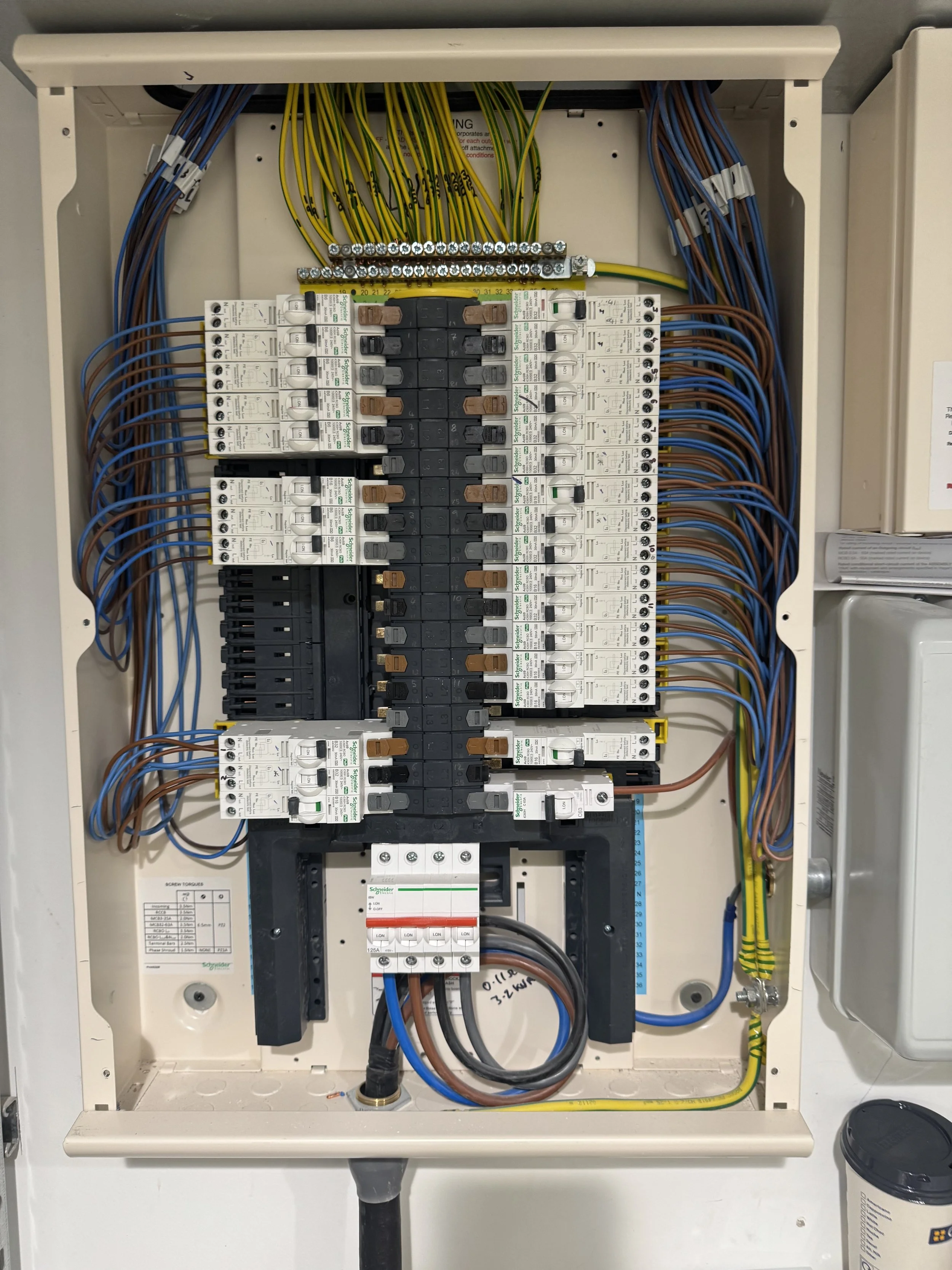 An electrical consumer unit with various switches, wires, and circuit components inside a metal enclosure.