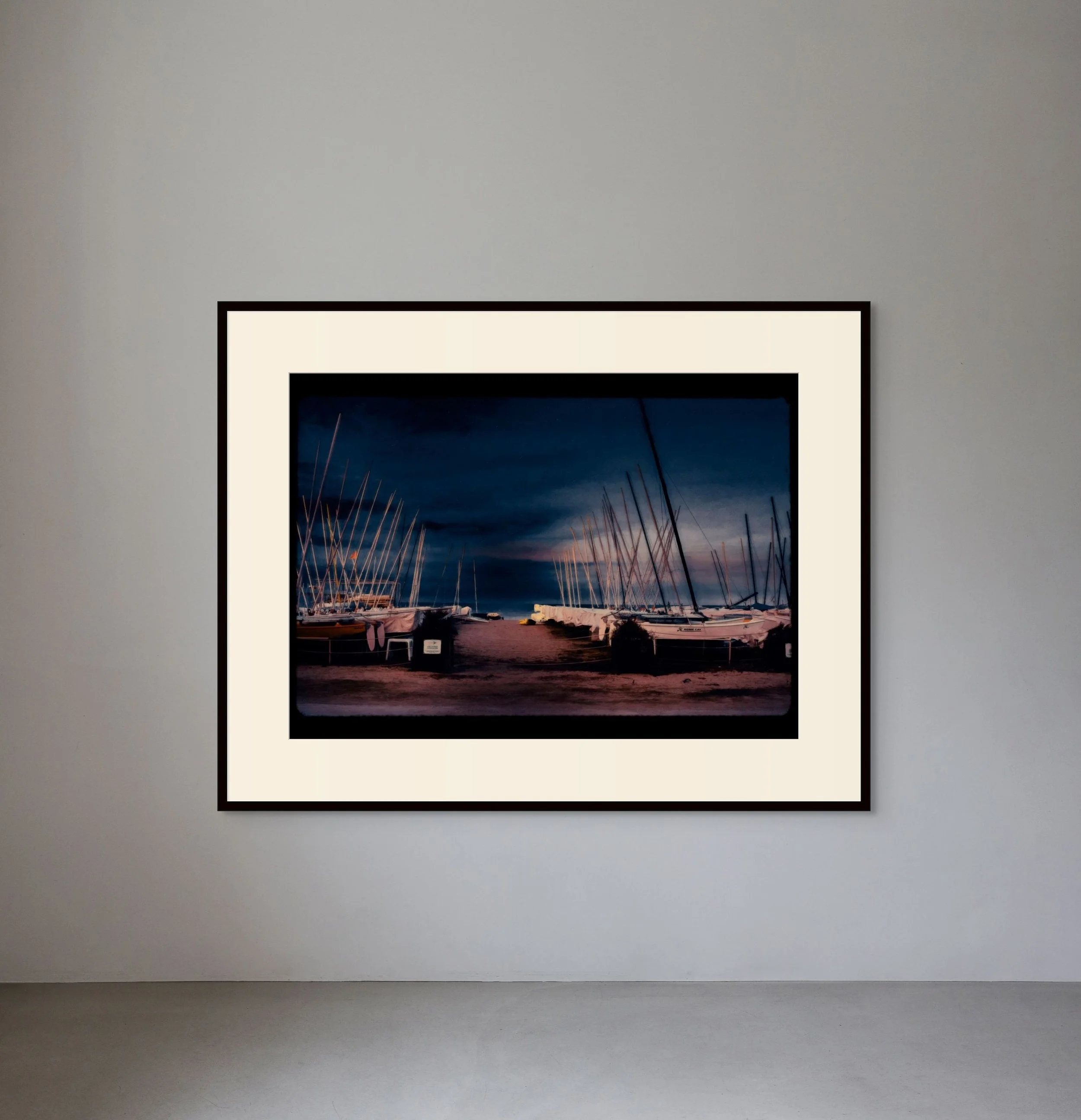 Framed photograph of a marina with sailboats docked at night, dark sky overhead.