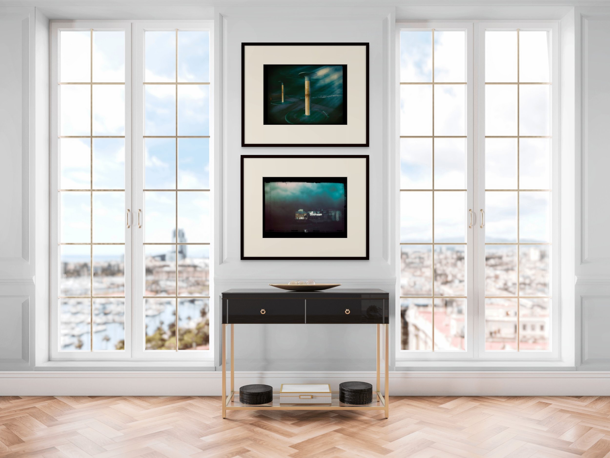 Living room with large windows overlooking cityscape, black and gold console table, and framed artwork on white wall.