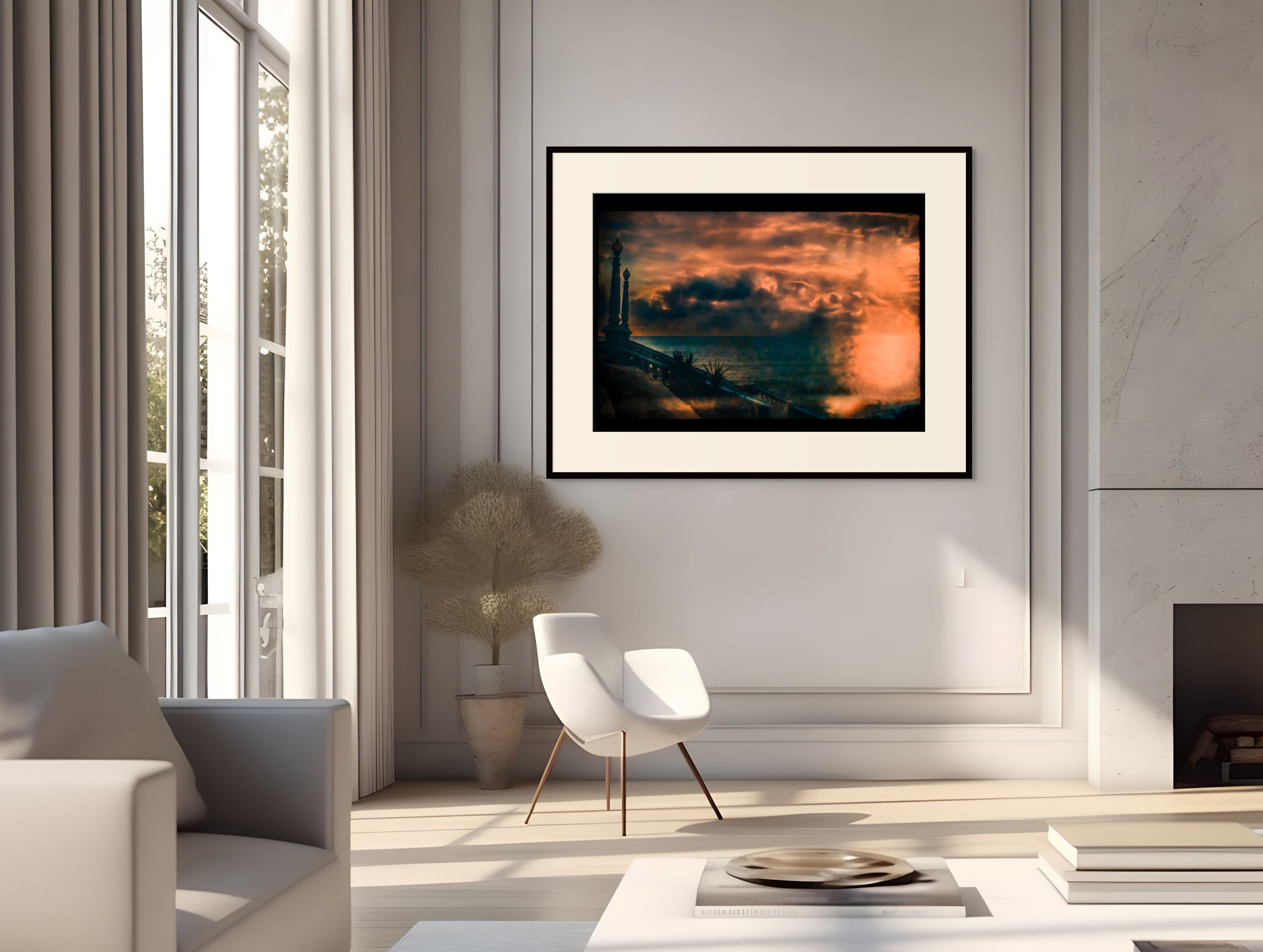 Living room with white furniture, large window with curtains, framed sunset ocean landscape photograph on the wall, decorative plant, and a white chair.