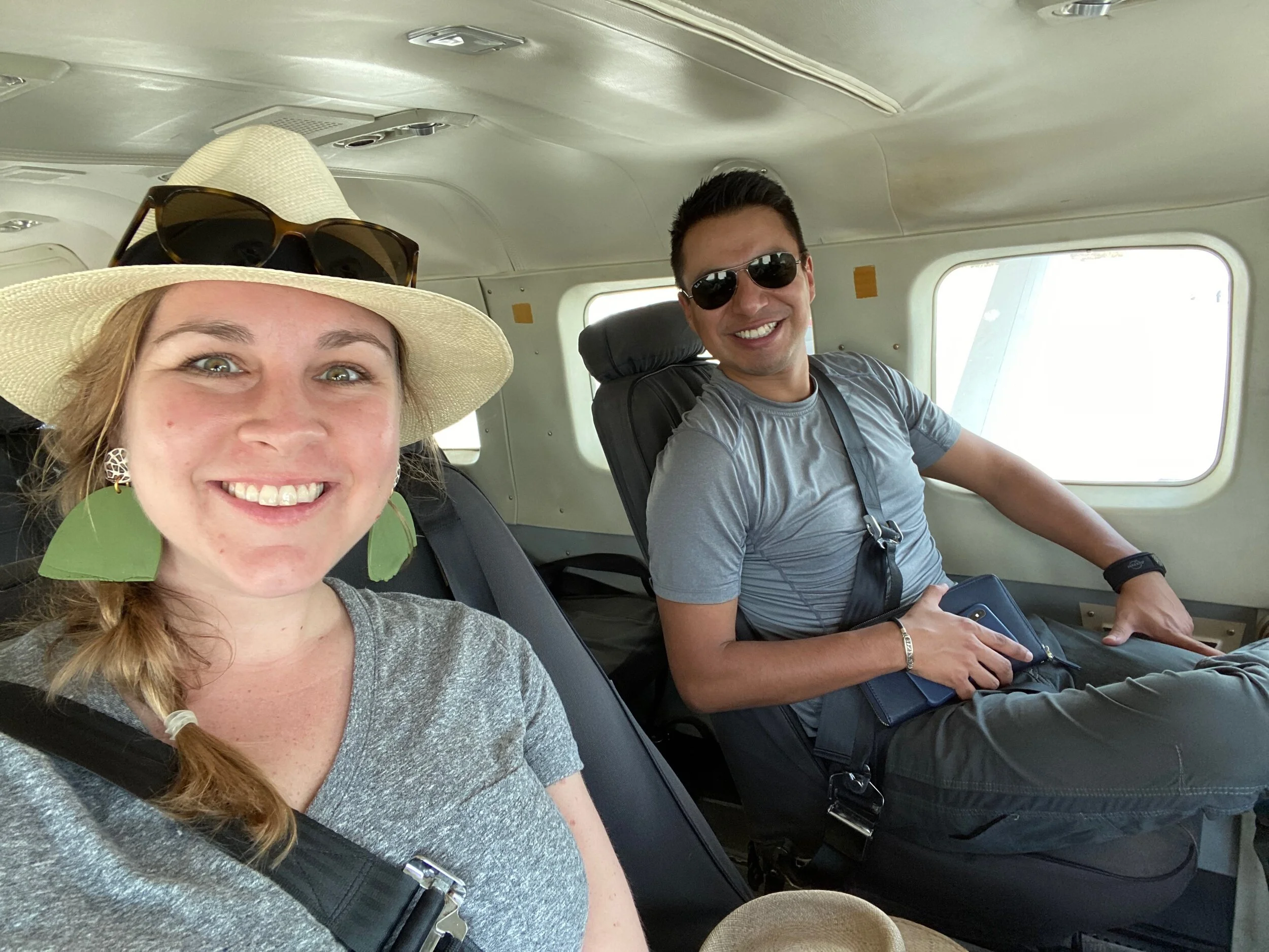 a couple sits in a small airplane smiling at camera