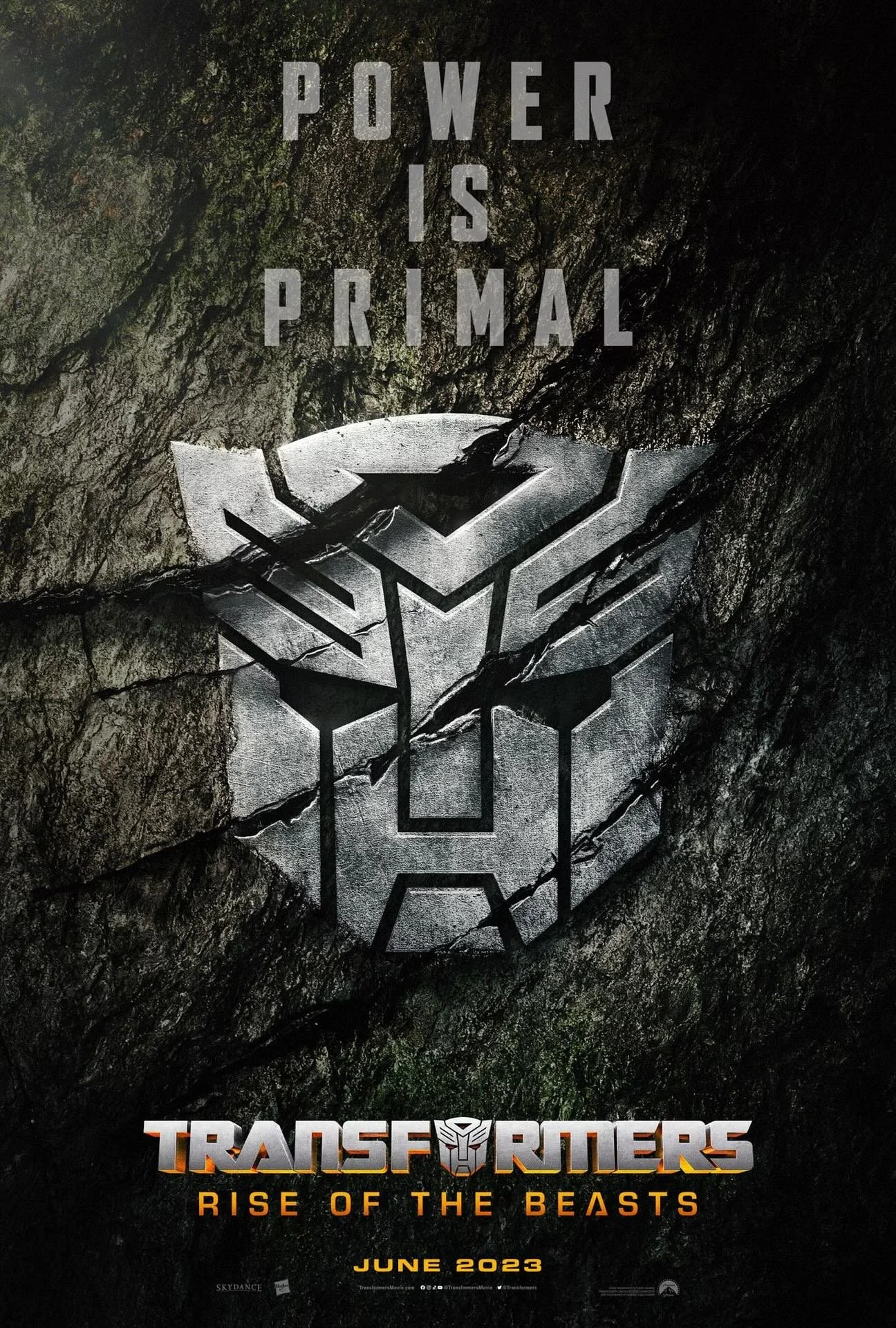 Poster for the movie 'Transformers: Rise of the Beasts' with the tagline 'Power is Primal' and release date June 2023. The poster features a metallic Autobot emblem embedded in a rugged, cracked stone background.
