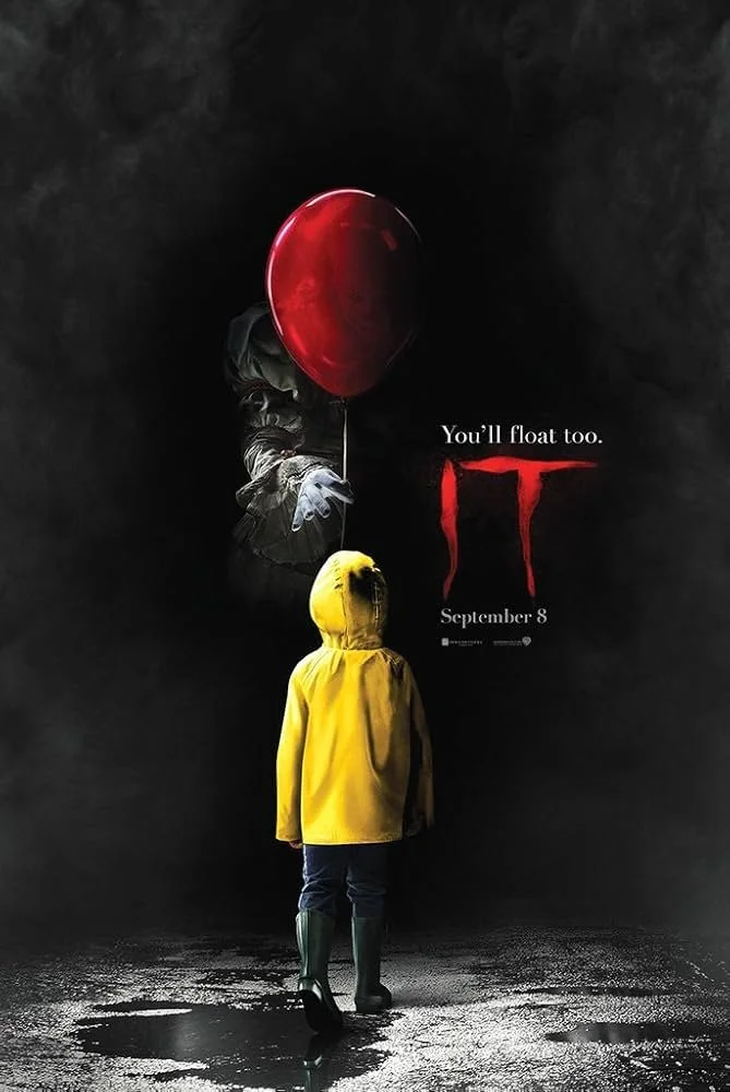 A person wearing a yellow raincoat and green boots standing on wet ground, looking at a poster for the horror movie 'It' featuring a red balloon and a clown's hand, with the text 'You'll float too.' and release date 'September 8'.