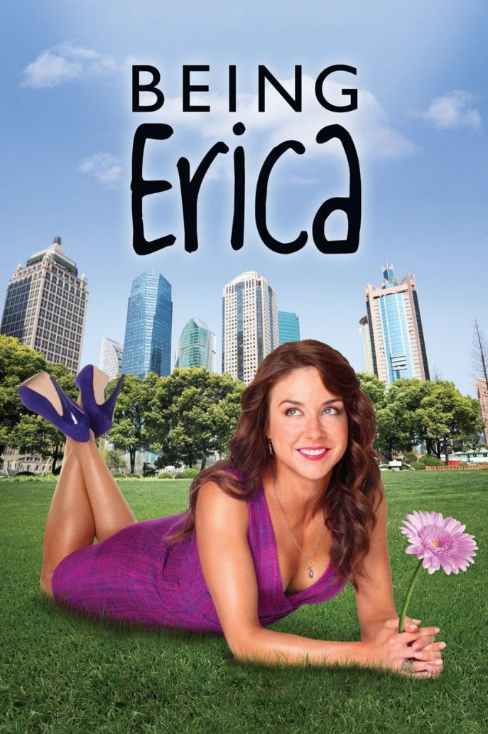 A woman in a purple dress and blue high heels lying on grass in front of a city skyline, holding a pink flower, with the text 'Being Erica' at the top.