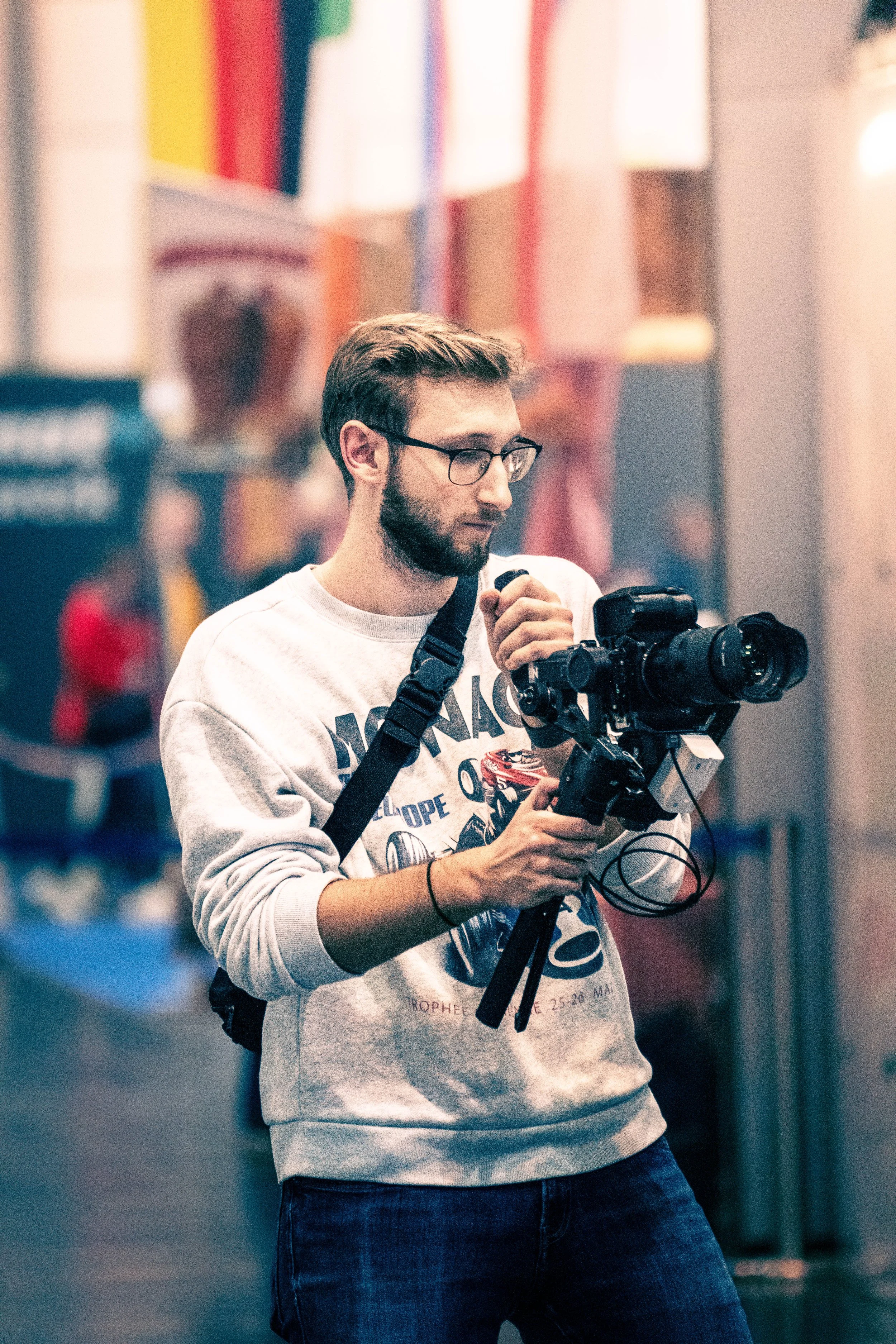Junger Mann mit Brille fotografiert mit professioneller Kamera in einer Ausstellung oder Messe.