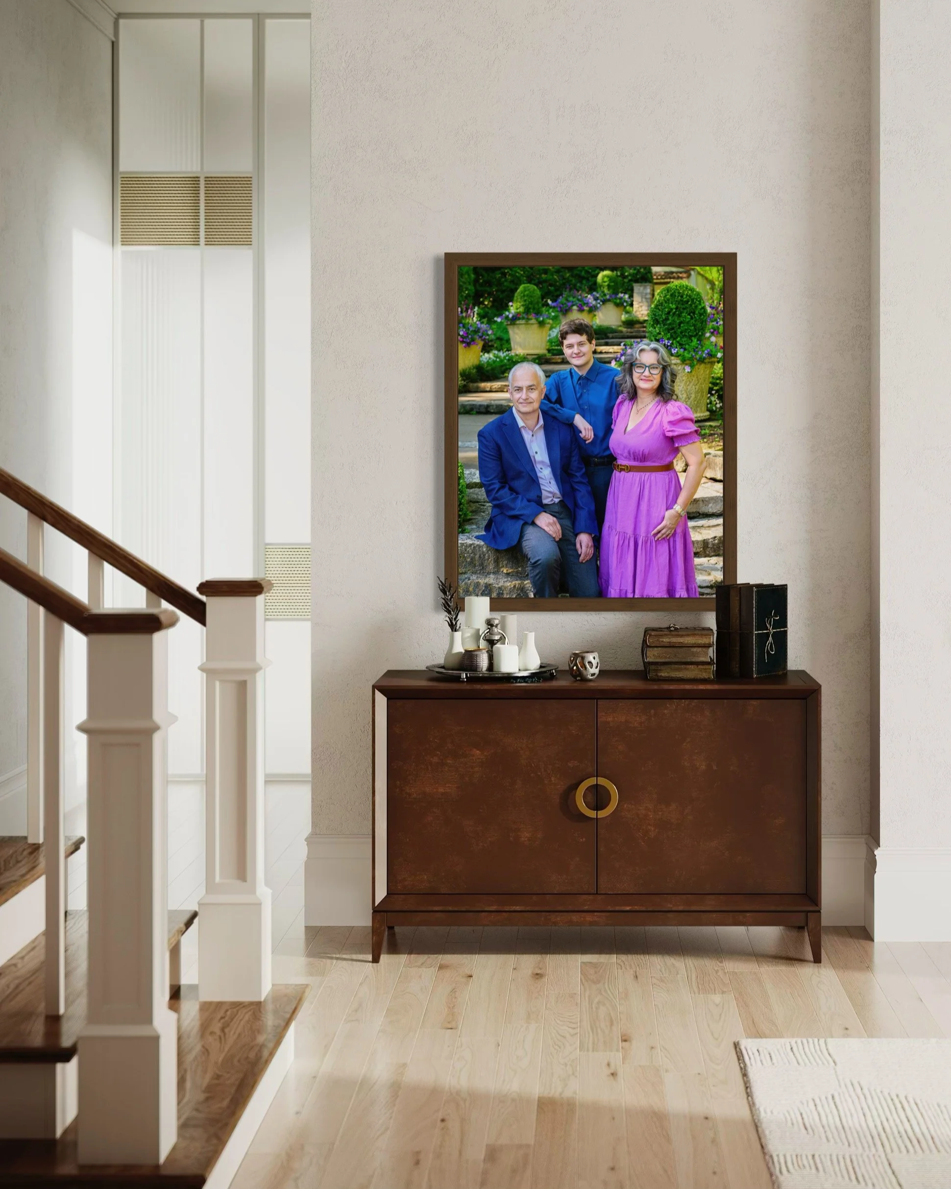 A framed family photograph on a wooden sideboard, showing three people outdoors in front of potted plants and flowers.