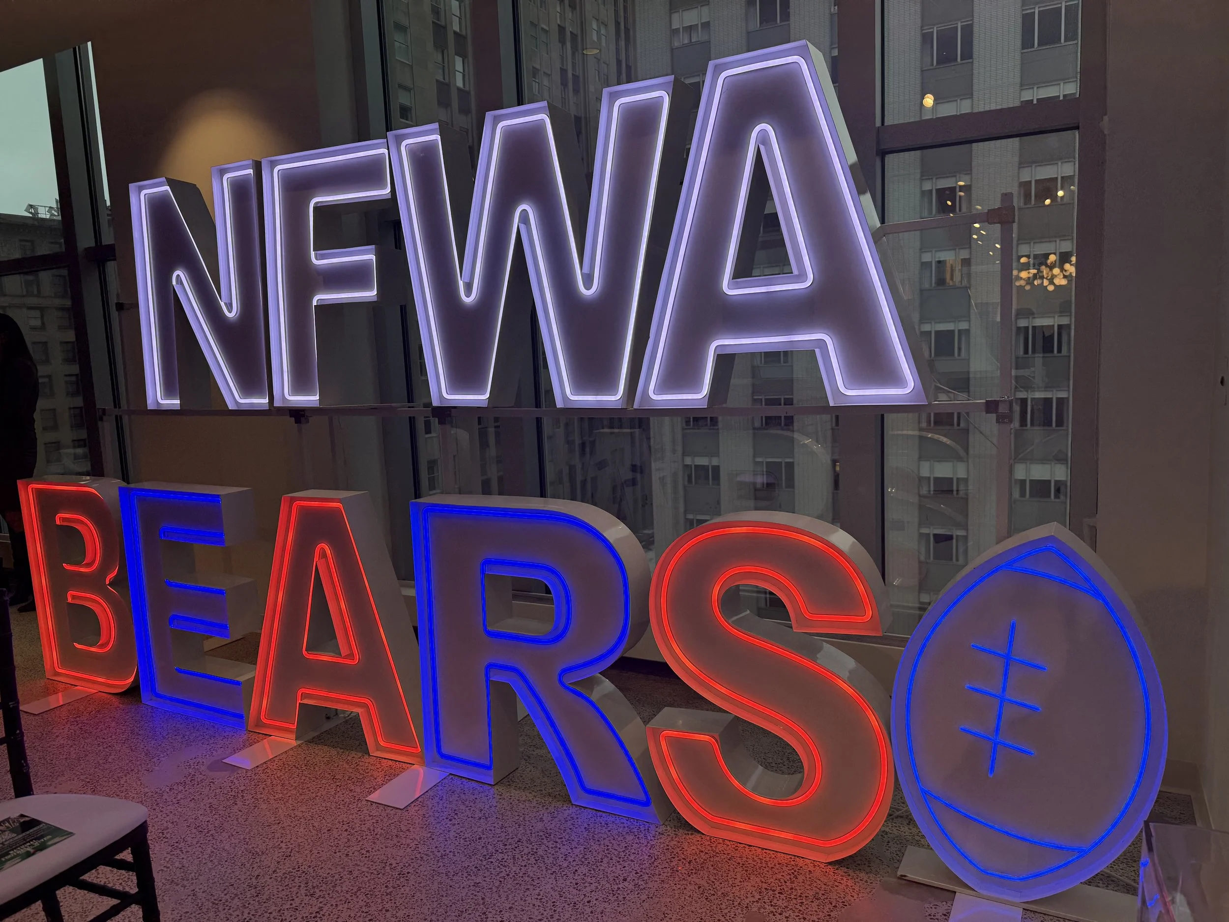 Neon sign displaying the words 'NEWA' in purple and 'BEARS' in red, blue, and white, with a blue bear paw print.