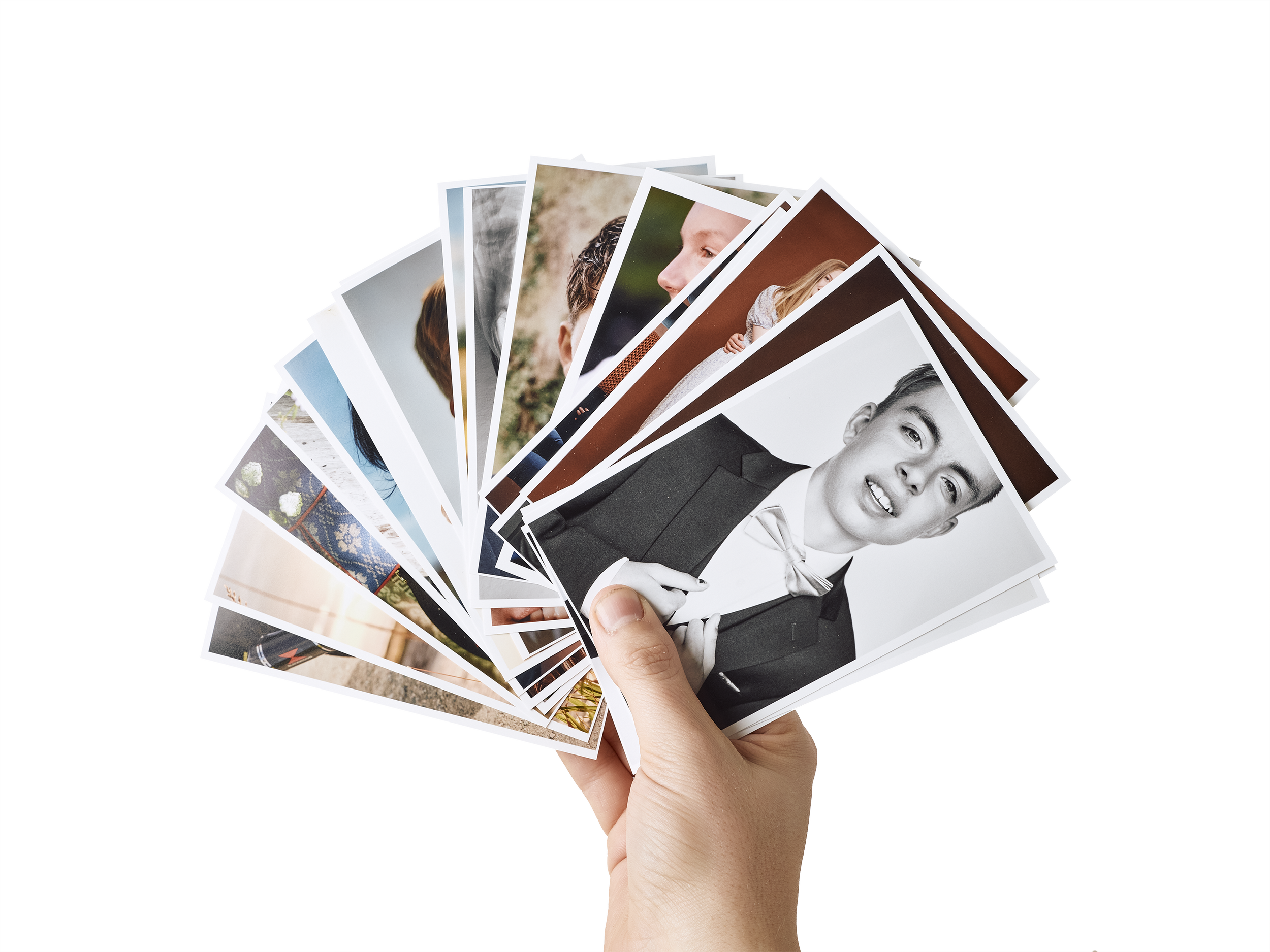 Hånd holder et utvalg av fotografier av mennesker, noen i farger og andre i svart-hvitt.