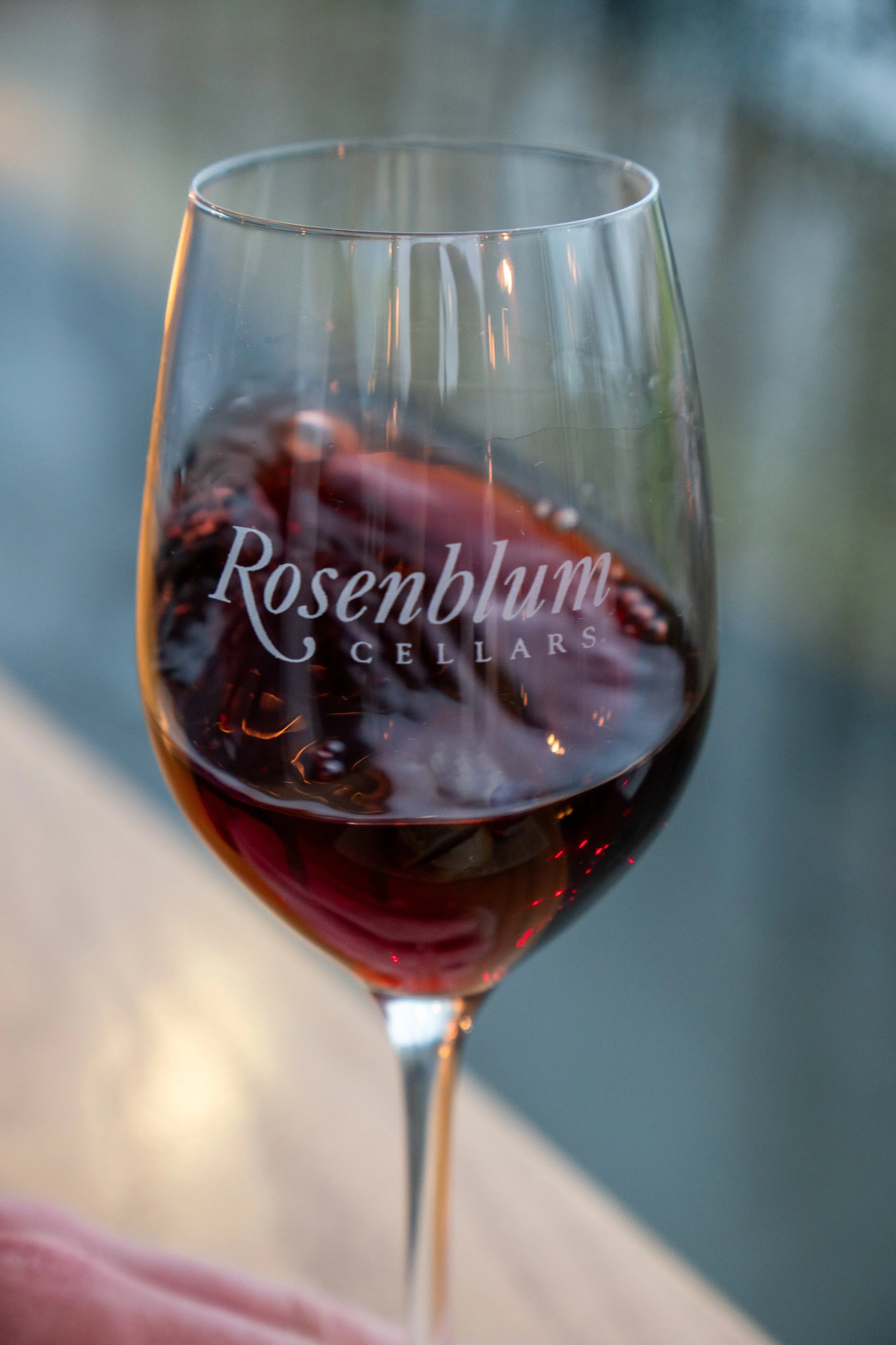 A glass of red wine with the logo of Rosenblum Cellars printed on it.
