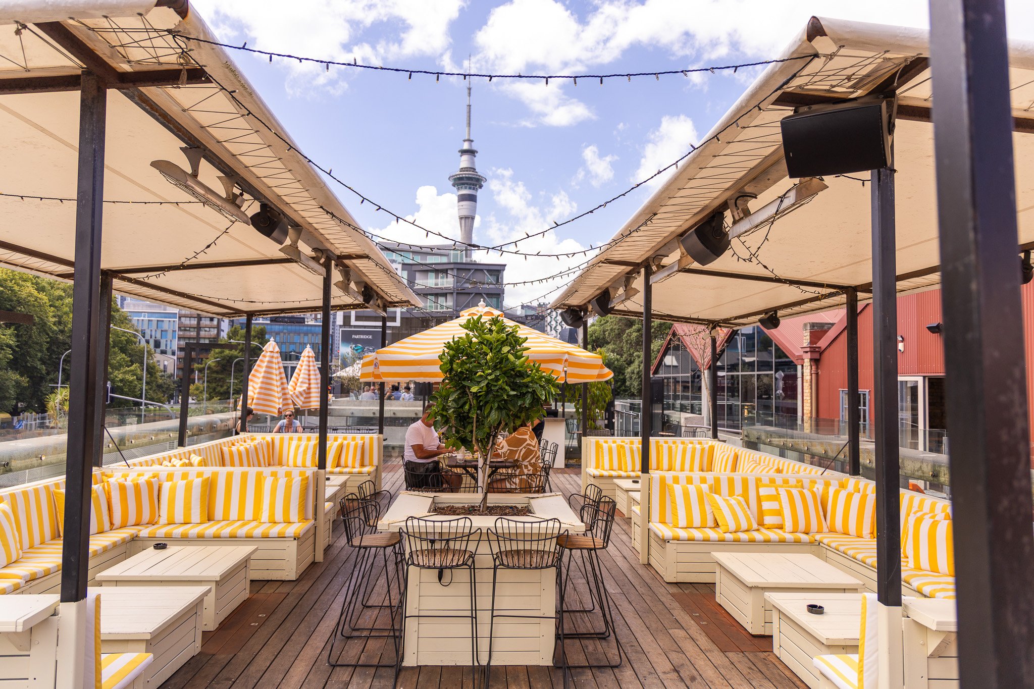 La Zeppa’s open-air sundeck with striped seating and views of the Sky Tower.