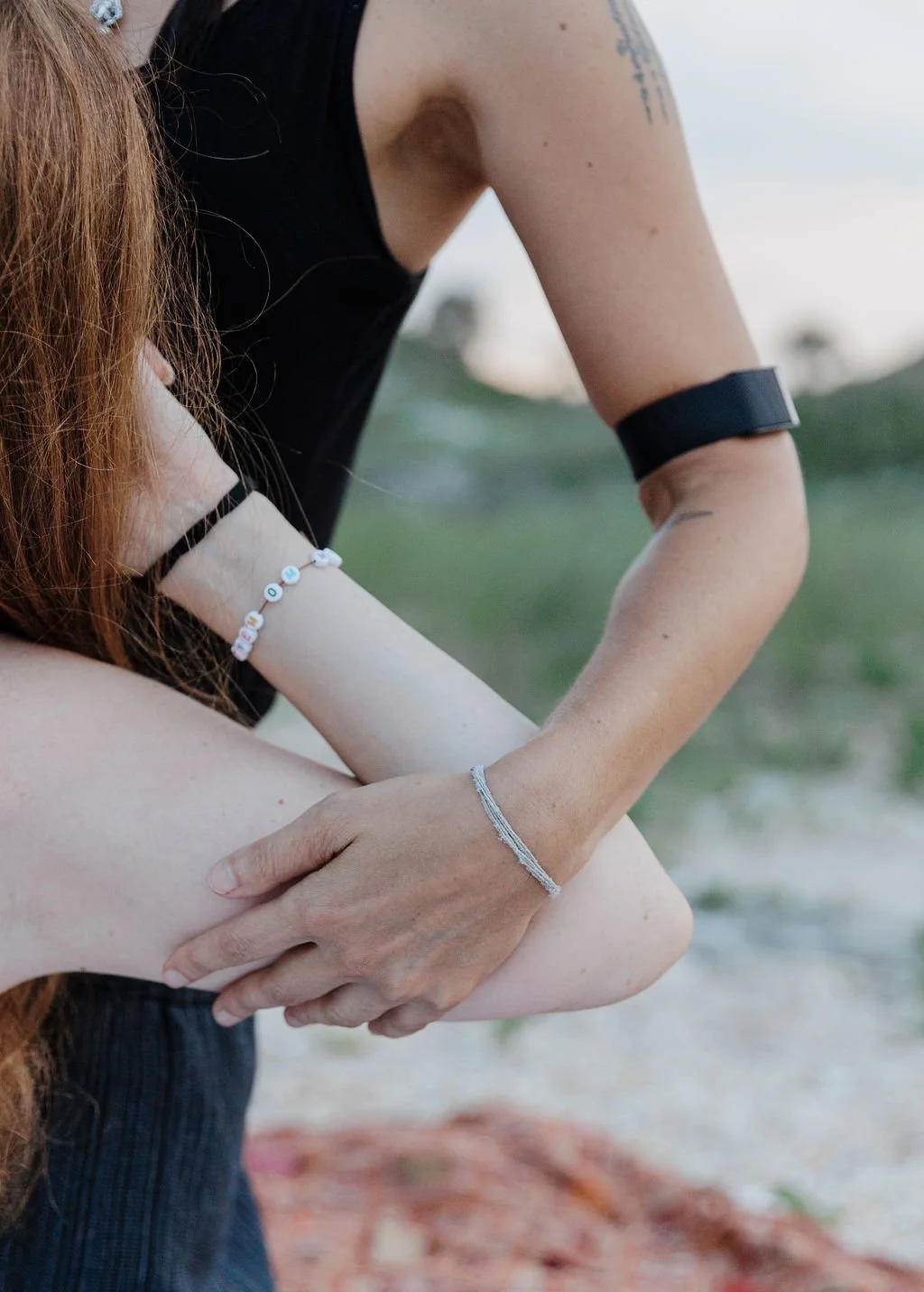A woman engaged in a Thai Massage on the beach, with the sun setting and casting a warm glow over the tranquil scene.